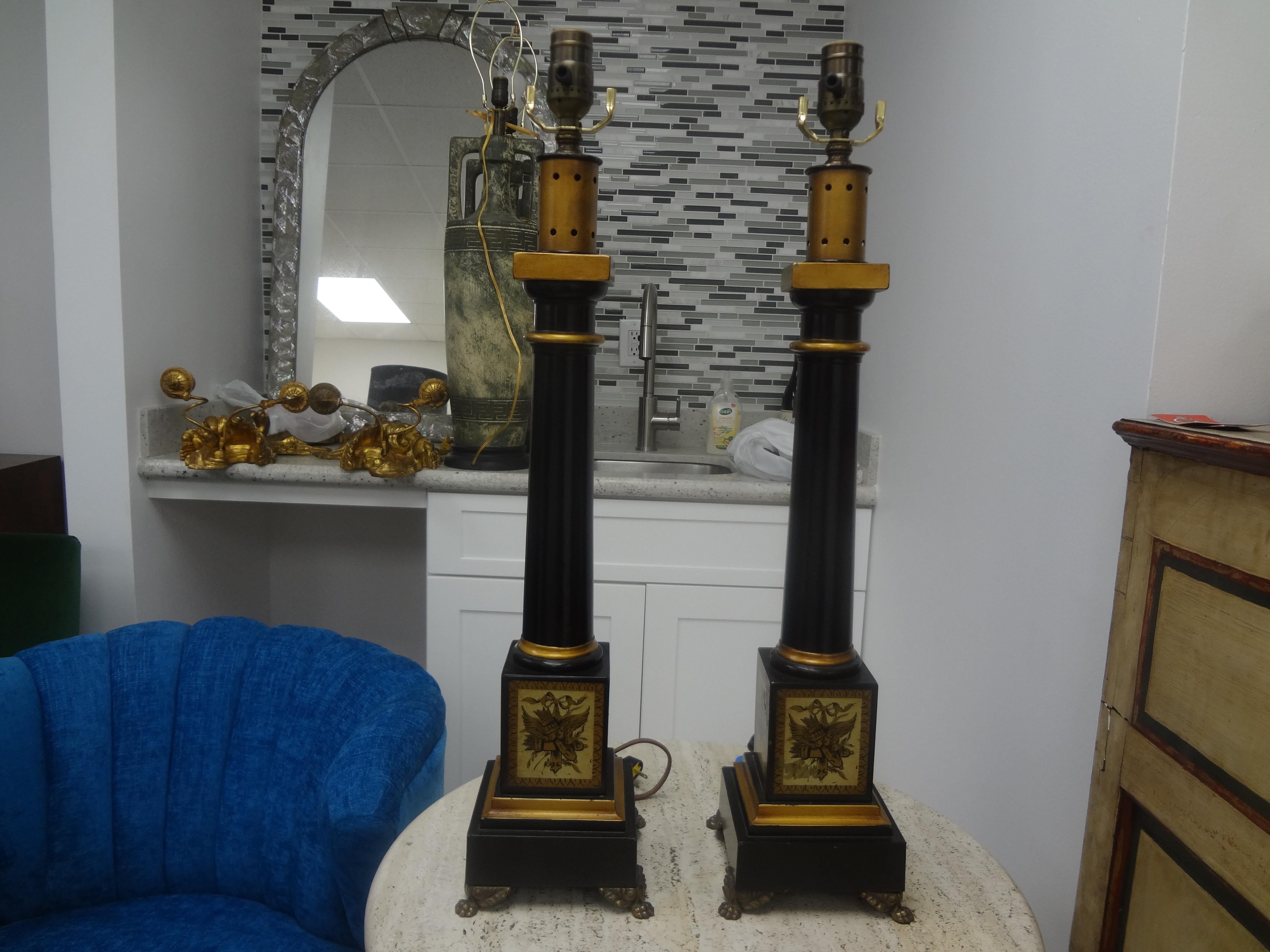 Pair of French neoclassical style tole lamps. This pair of French neoclassical style tole lamps were executed in beautiful black and gold with a stunning neoclassical motif on the bases with bronze paw feet. These lamps have been newly wired with