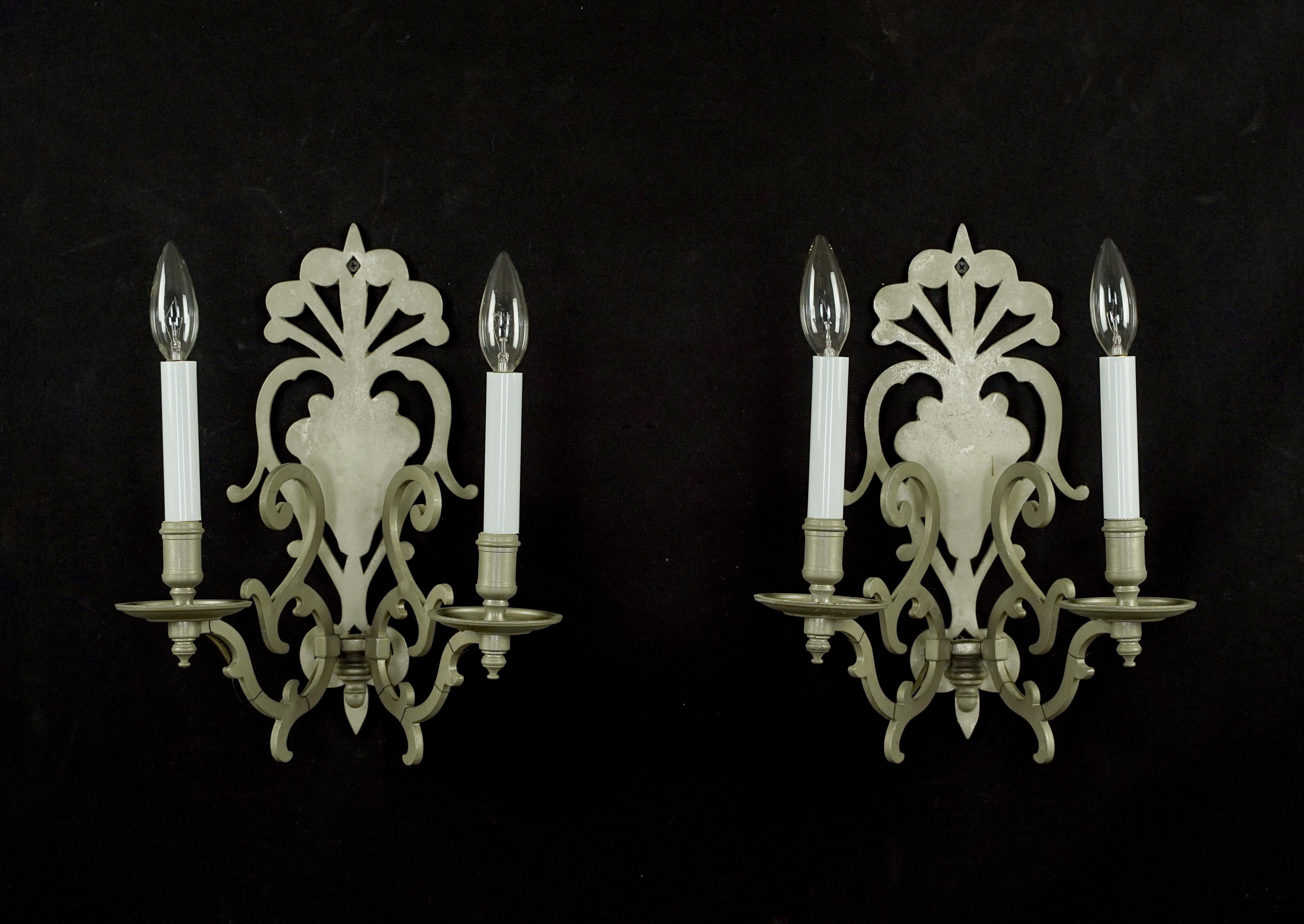 Applique a due bracci in stile francese realizzate in metallo con finitura nichel. Ogni applique richiede due lampadine a candelabro e-12. Il prezzo include il restauro, la pulizia e il ricablaggio. Buone condizioni con usura superficiale dovuta