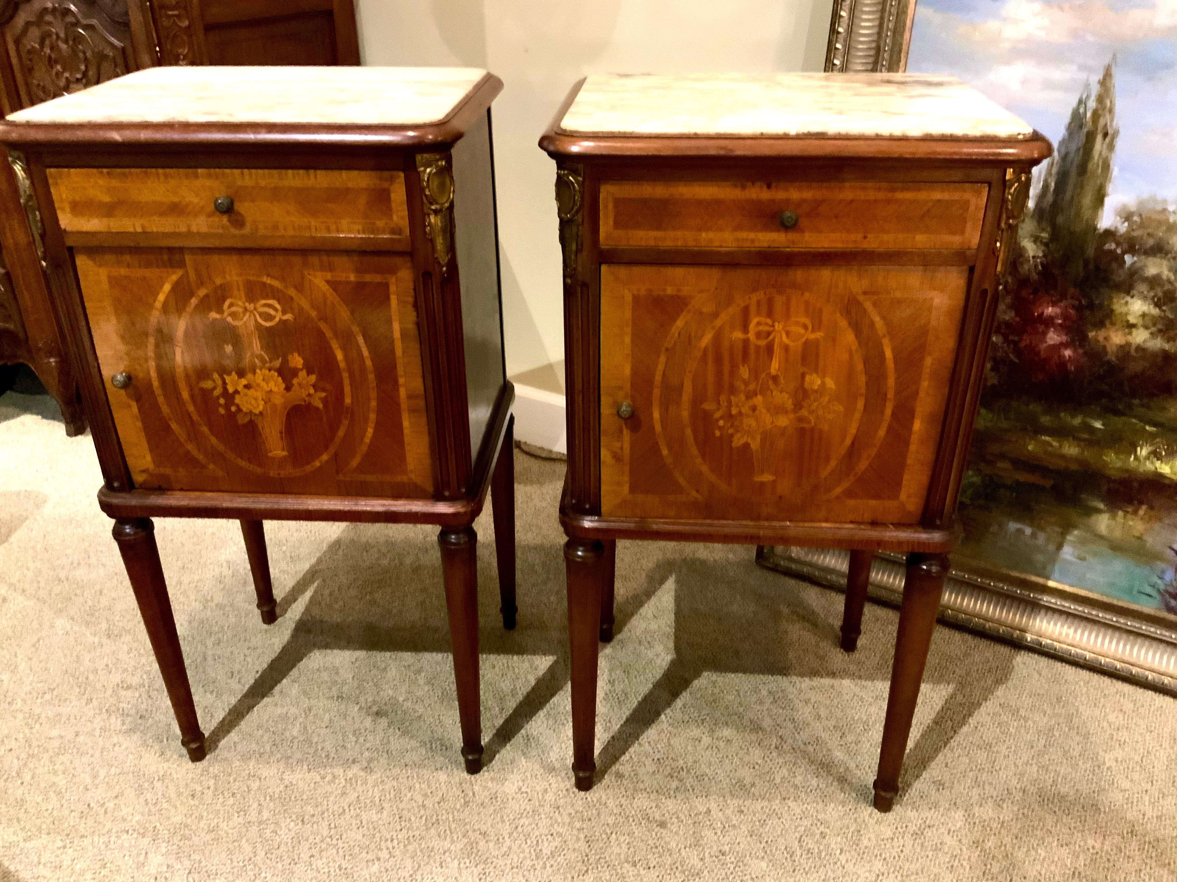 Exceptional marquetry work make this pair especially terrific.
A basket of flowers in marquetry is centered on the front door
Of this piece. A creamy white and beige marble grace the top of
These pieces. A slender shaped leg make these pieces