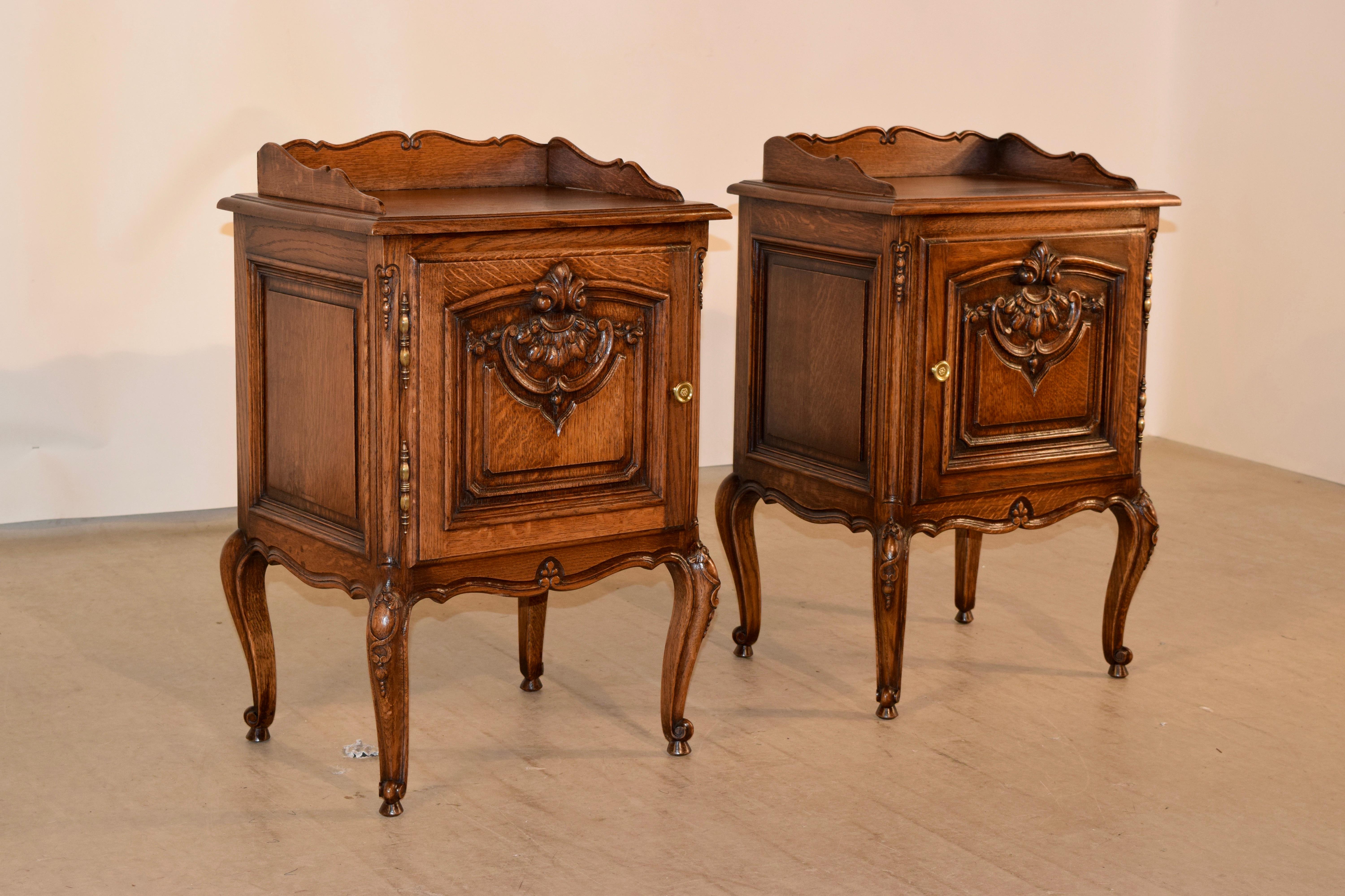 Pair of French bedsides made from oak with scalloped galleries circa 1900, following down to hand raised panels on three sides and raised and hand carved doors in the front, which open to reveal storage. Supported on hand carved cabriole legs,