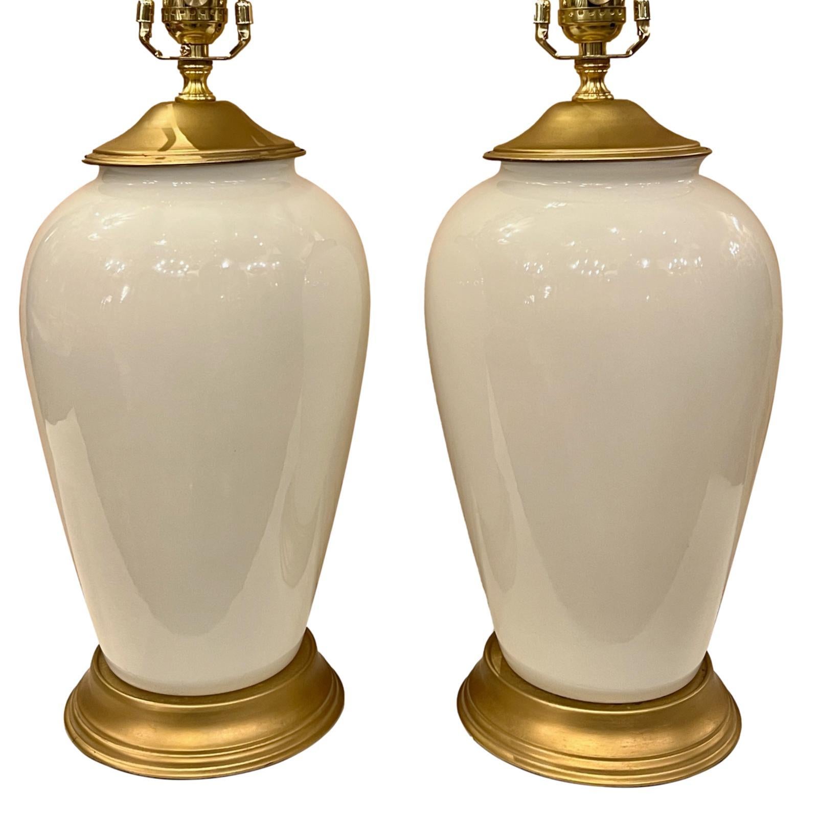Paire de lampes françaises en verre opalin des années 1950 avec des bases dorées.

Mesures :
Hauteur du corps : 14
Hauteur jusqu'à l'appui de l'abat-jour : 24