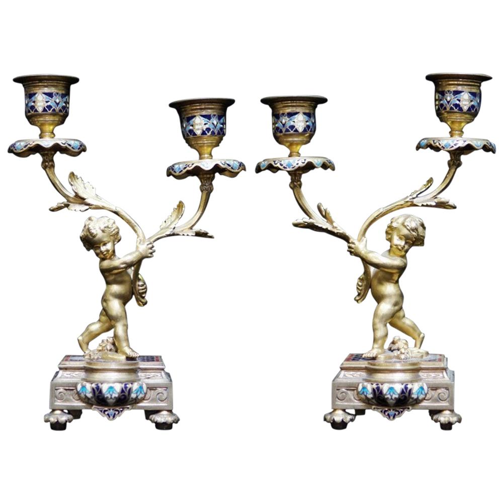 Exquisite pair of 19th century French Louis XV style ormolu and champleve two light candlesticks. 
Each candlestick is with a putti a foliage decorated candle-arm, terminating in a Champleve and ormolu candle holder, all supported by a finely