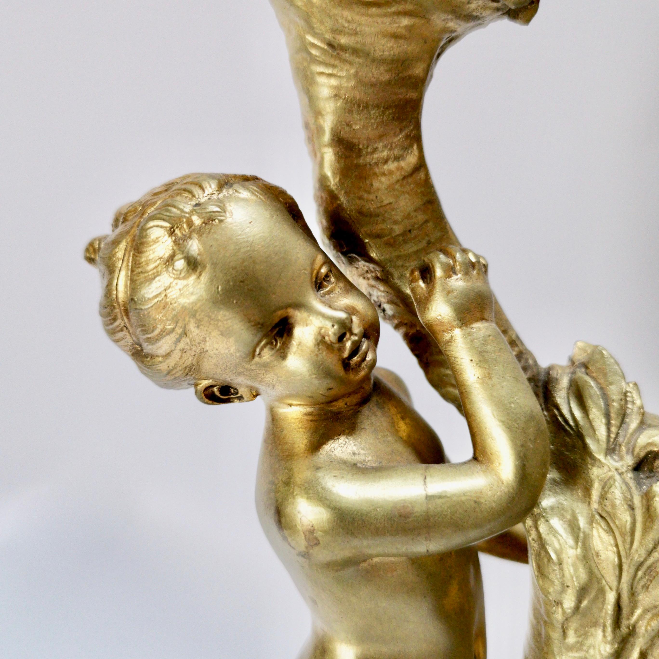 This is a pair of candelabra made of ormolu on a marble base, made in France in circa 1875. The candelabra are made in the Rococo Revival style and each have a boy and girl cherub holding up the sconces, which are shaped like cornucopia. The