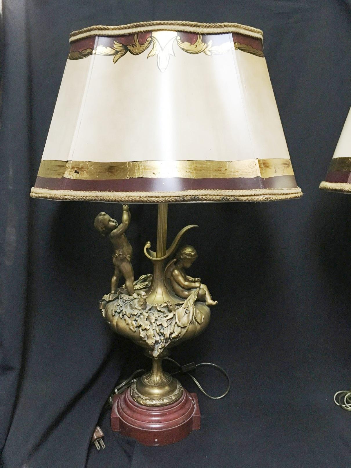 Outstanding opposing pair of 19th century French Louis XVI style ormolu lamps with rouge marble bases.
With parcel gilt and paint decorated faux parchment shade.

Each ormolu lamp depicting a seated cupid and a standing putto on ewer-form body