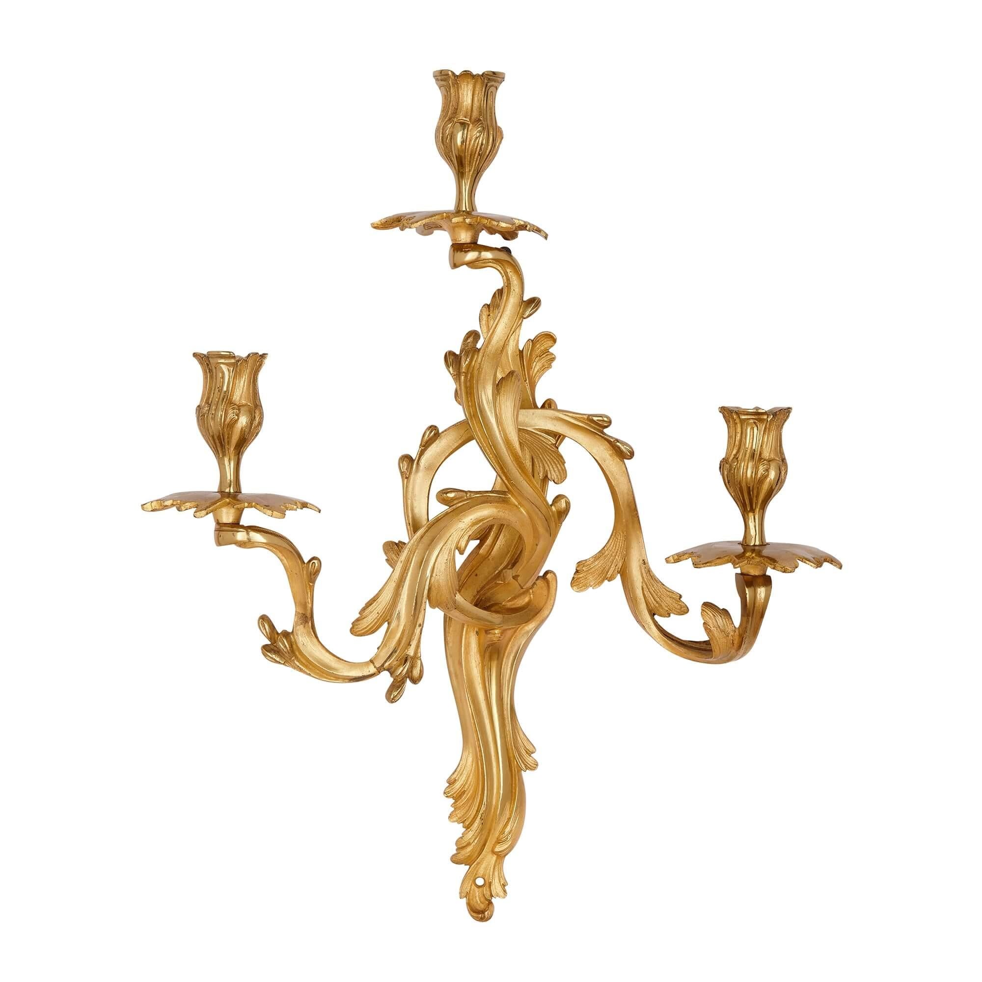 Pair of French Ormolu wall lights in the Louis XV style.
French, Late 19th century.
Measures: height 45cm, width 40cm, depth 15cm.

Cast in gilt-bronze, and designed in an exuberant, radiant Louis XV style, with interweaving branches and a host