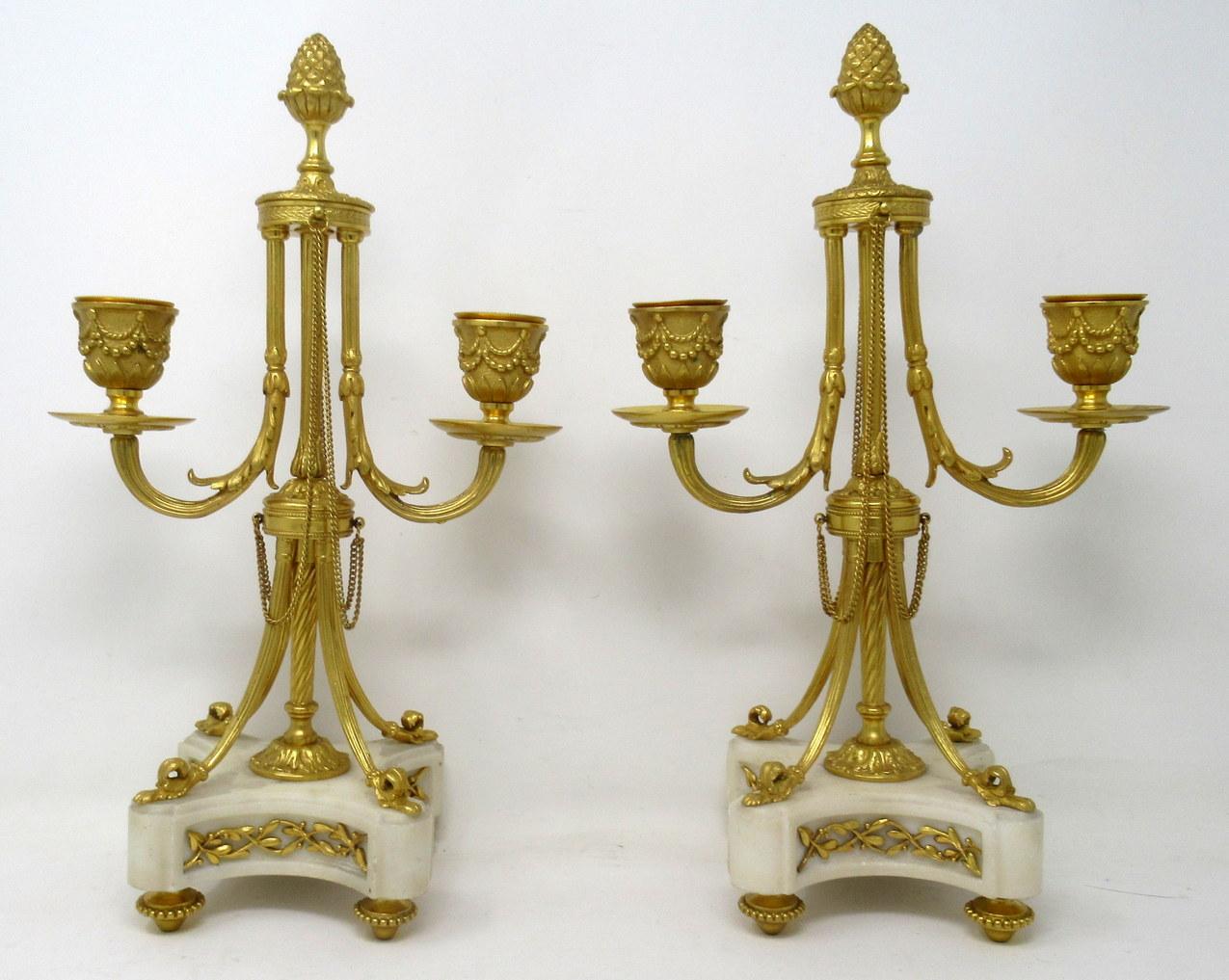 An exceptionally fine quality pair of French gilt bronze and statutory cream marble twin arm candelabra of medium proportions, made during the third quarter of the 19th century.

The finely chased candle sconces issuing from scrolling arms