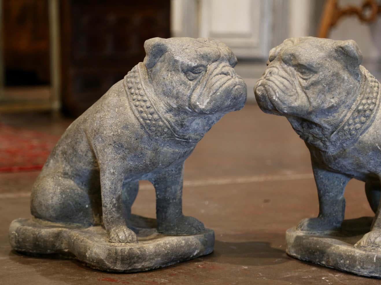 Carved of stone in France circa 1980 and set on a shaped base, the vintage garden figures feature two English bulldogs sitting on their back legs. The dogs dressed with a thick studded collar around the neck have wonderful facial expressions. The