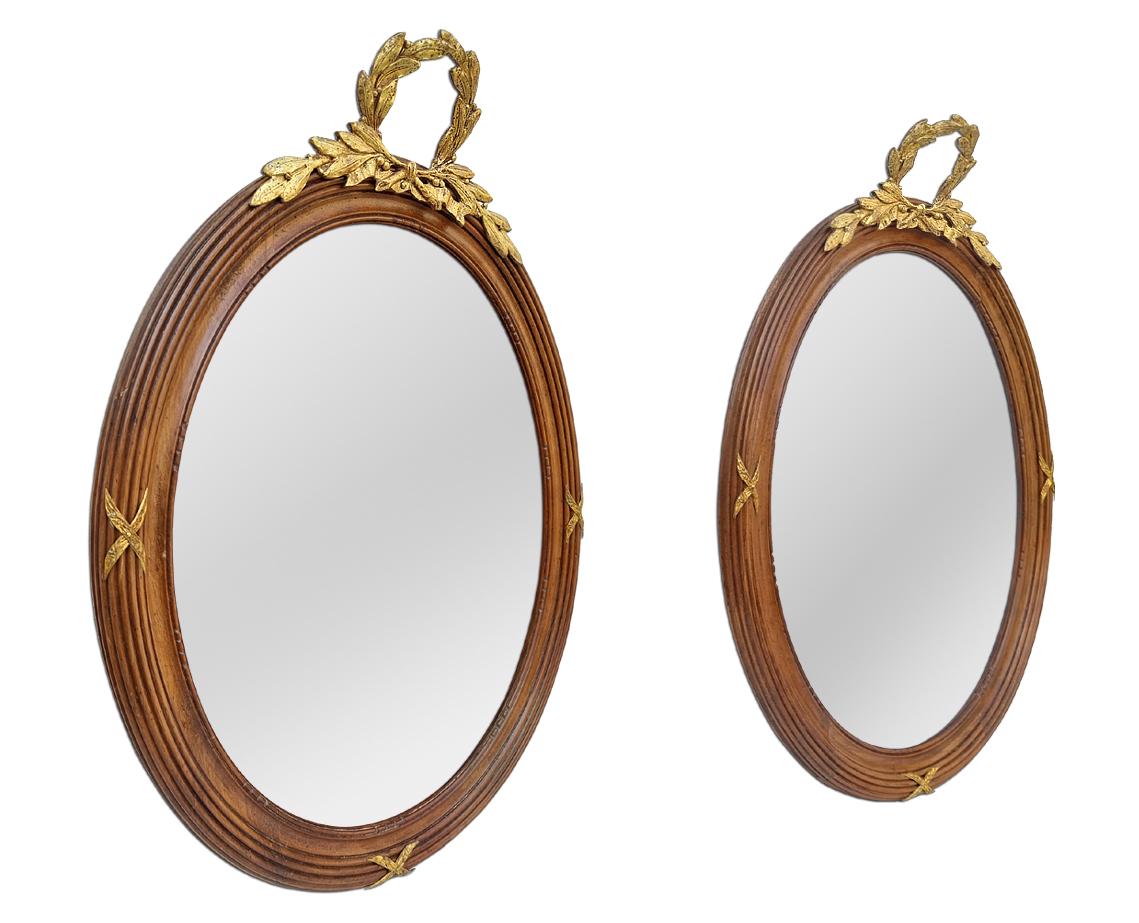Pair of antique oval mirrors, circa 1890. Antique French mirrors Louis XVI style inspiration. Oval carved wood grooves frames with a gilded bronze shell and 3 gilded bronze ornaments (crosses shapes) around wooden frame. Antique frame width: 5.5 cm