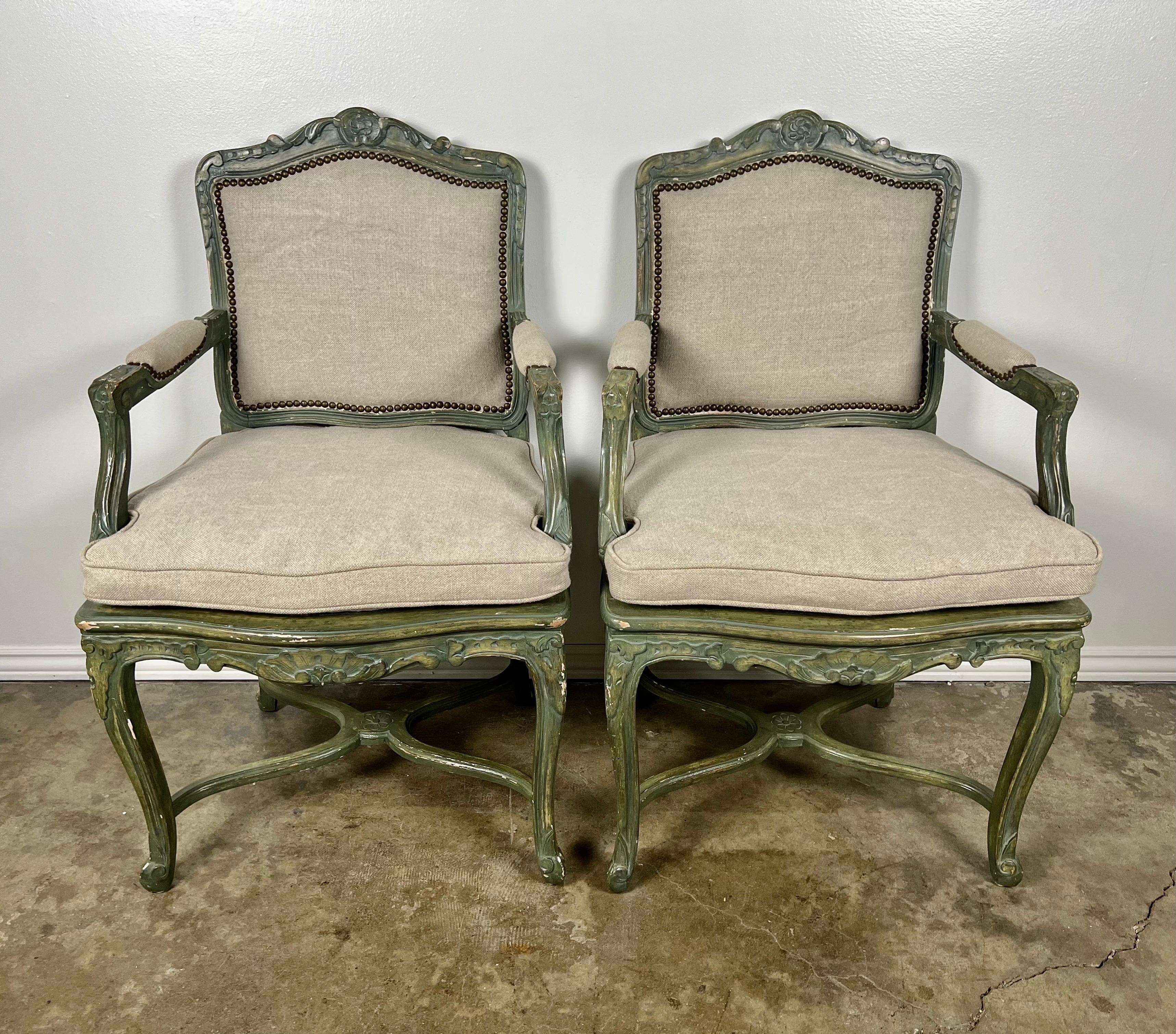 Pair of 19th century carved painted armchairs standing on four cabriole legs with rams head feet. Newly upholstered in a washed Belgium linen with nailhead trim detail. Loose cushions with original cane underneath.p