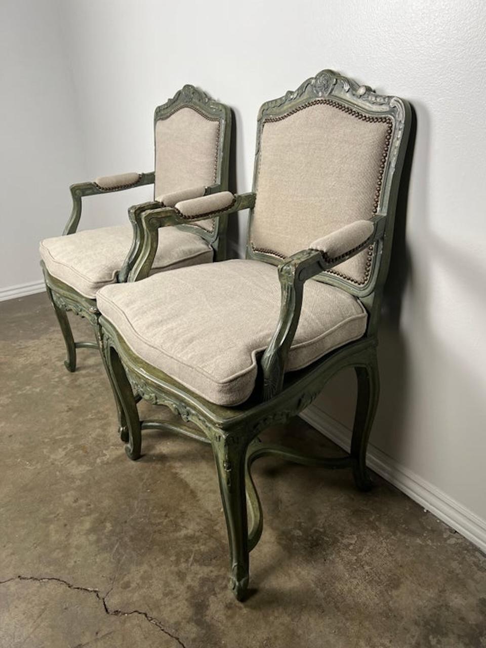 Pair of 19th century carved painted armchairs standing on four cabriole legs with rams head feet. Newly upholstered in a washed Belgium linen with nailhead trim detail. Loose cushions with original cane underneath.