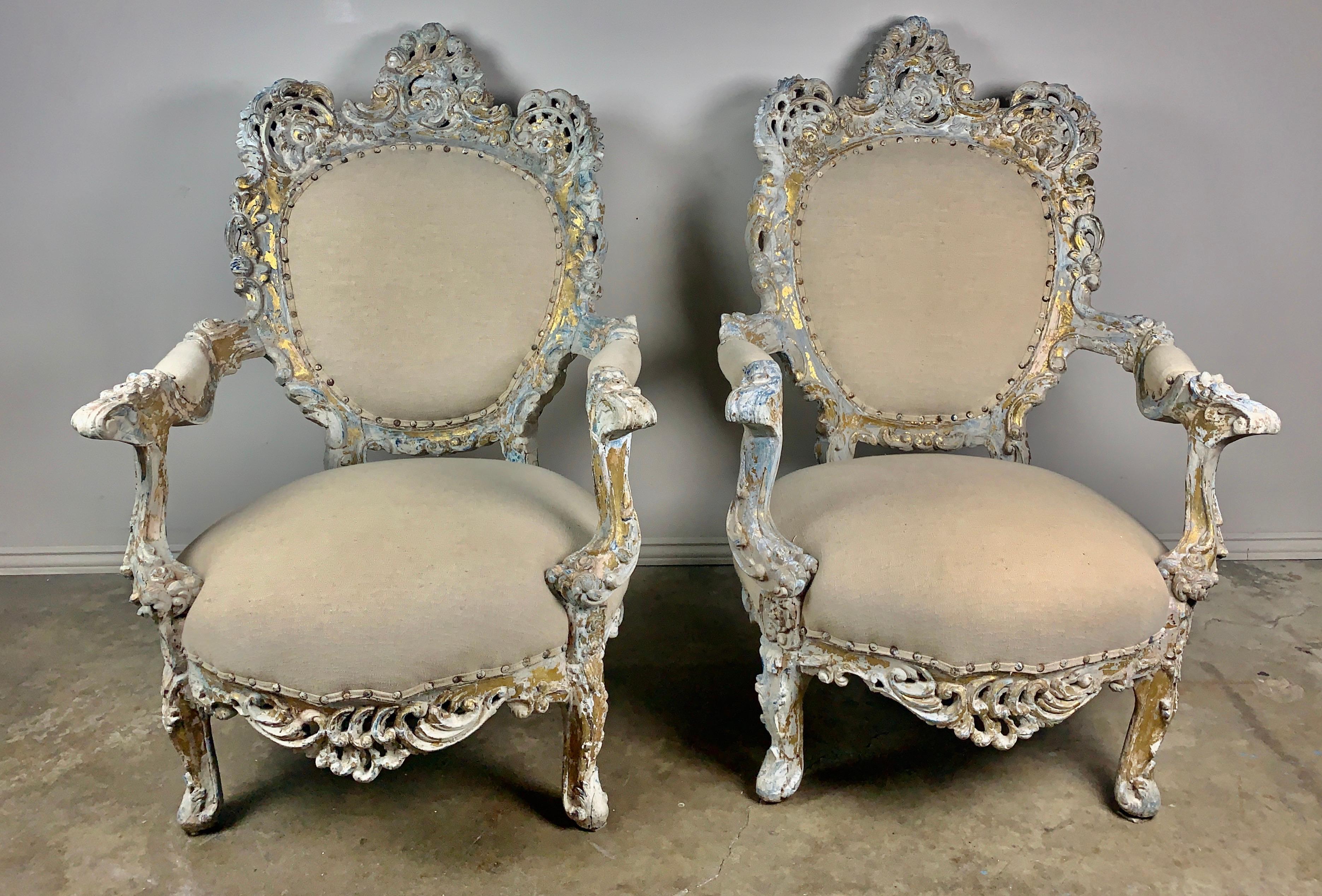 Pair of 19th century French painted and parcel gilt Rococo style armchairs upholstered in an oatmeal colored Belgium linen with original nailhead trim detail.
   