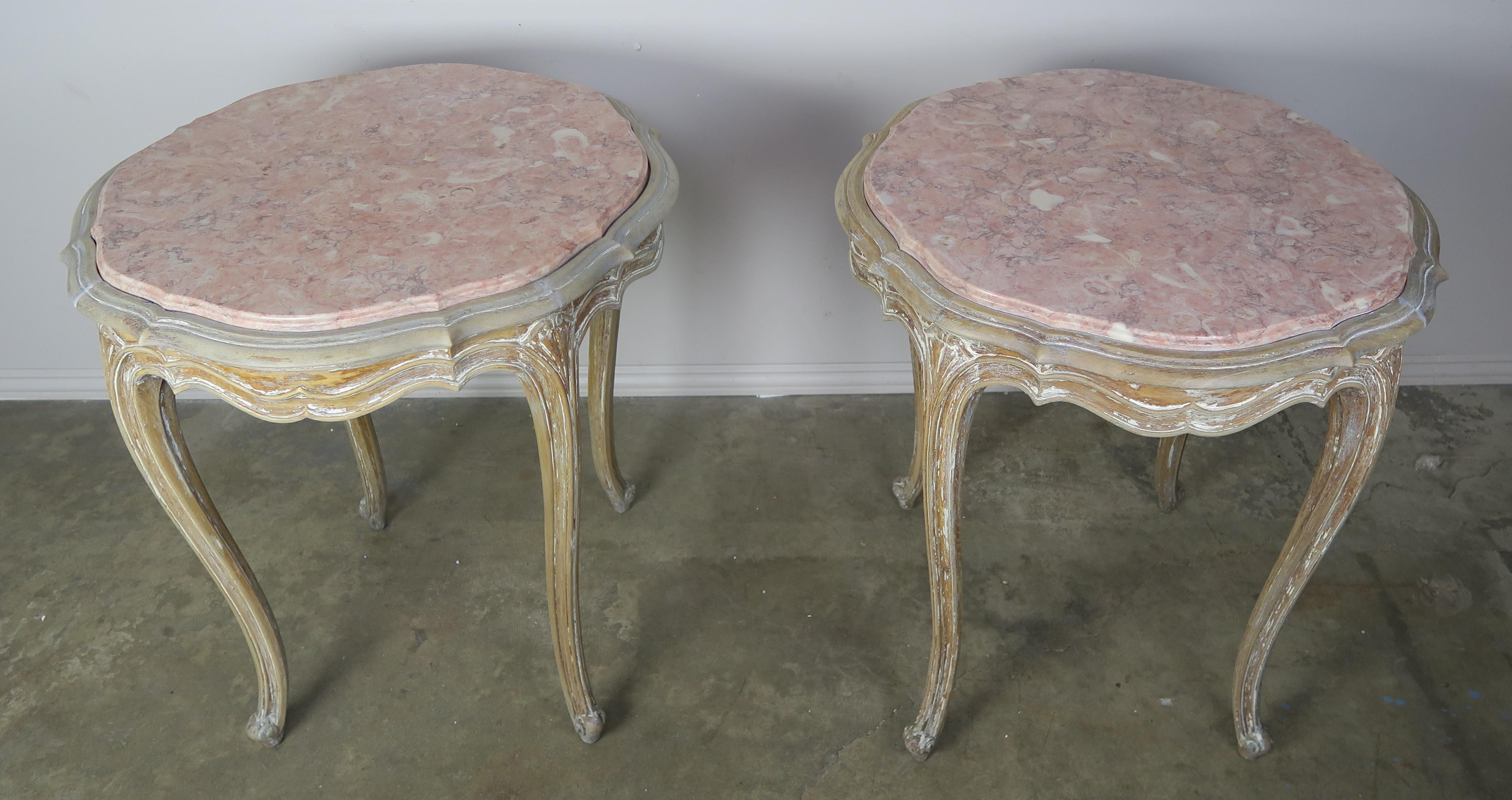 Pair of French painted marble top tables. Remnants beautiful worn paint can still be seen throughout the finish. The soft pink colored marble tops, rosa tea, is the perfect color to coordinate with the painted bases. The tables stand on four