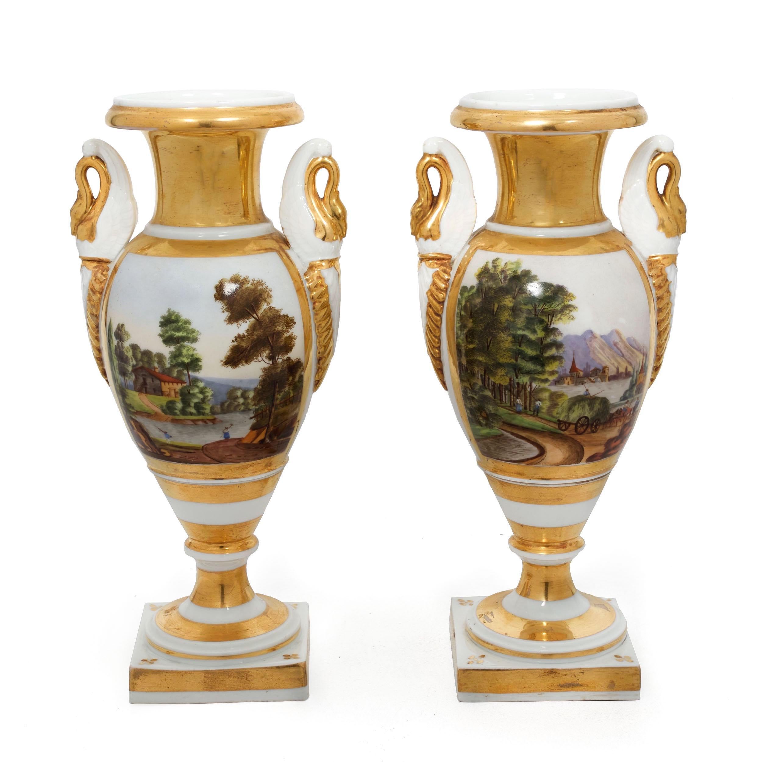 An attractive pair of 19th century parcel-gilt white-porcelain vases with painted scenes of countryside landscapes, three depicting castles and manors before various lakes and the fourth with donkeys and farmers working the grounds before a large