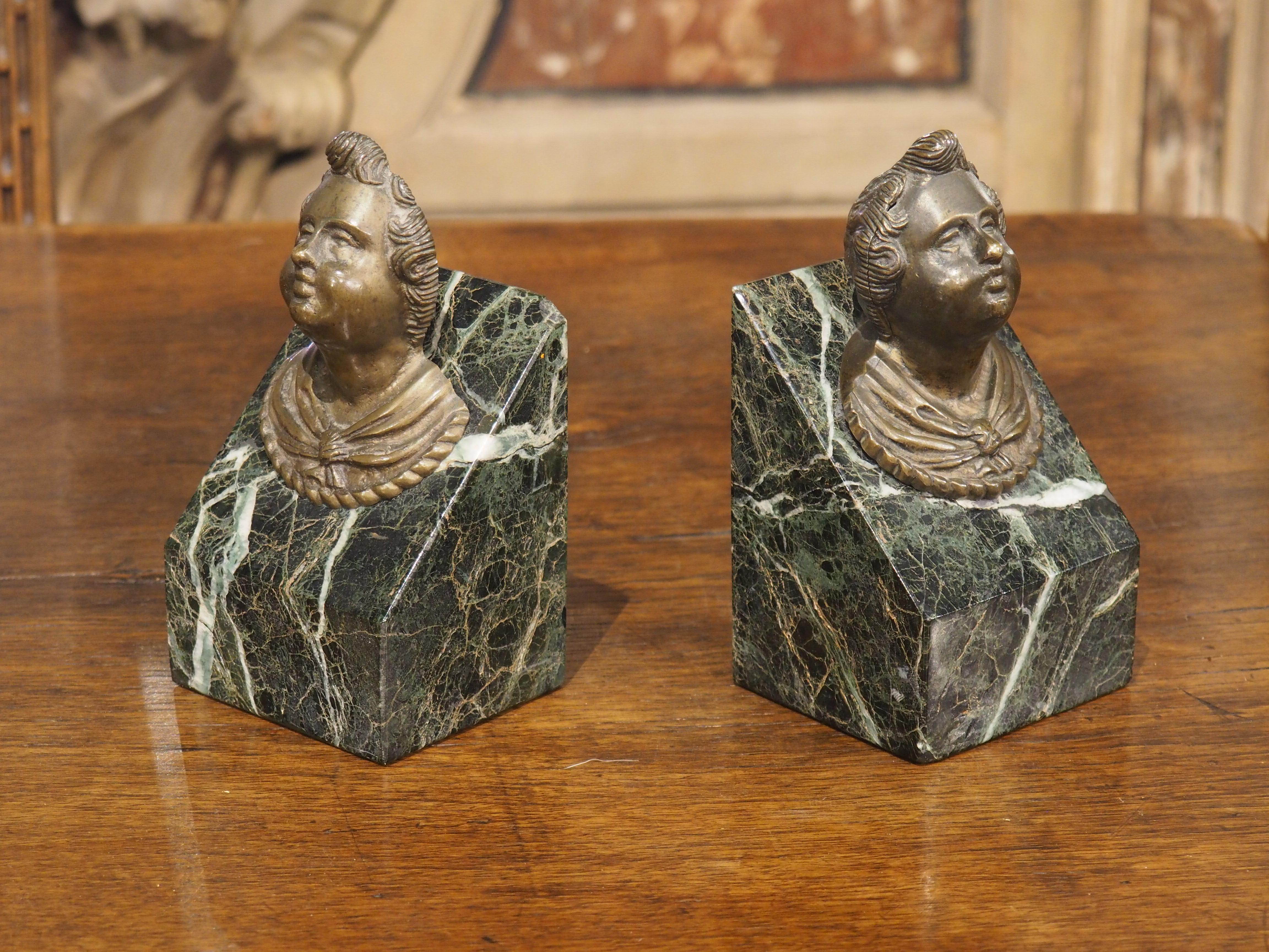Queste teste di putti francesi in bronzo patinato, circondate da scanalature a spirale, sono montate su plinti di marmo dalla forma geometrica. Risalenti al 1700 circa, i busti in rilievo sono caratterizzati da un cherubino con i capelli ricci che