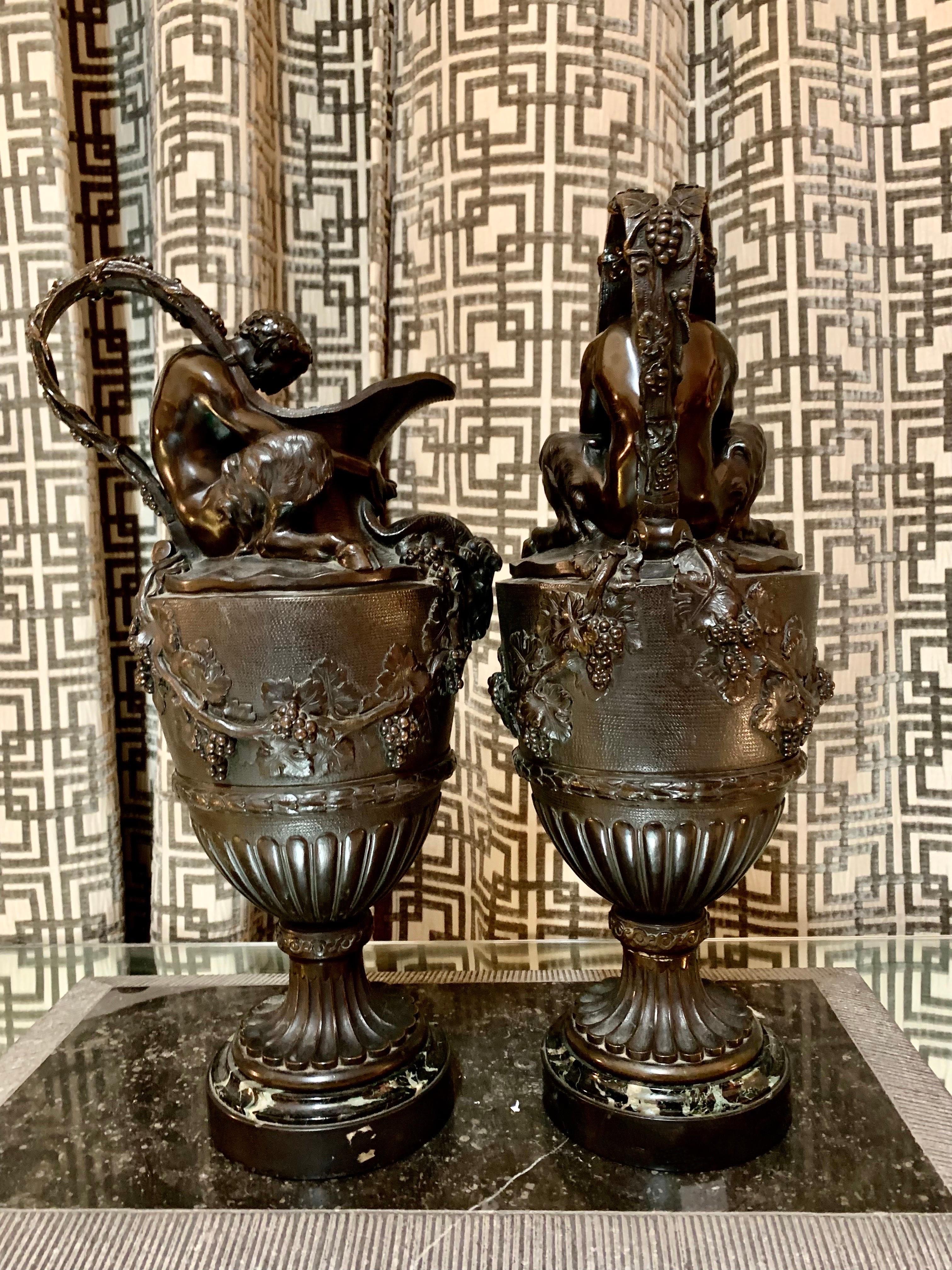 Ein Paar französische Vasen oder Urnen des späten 19. Jahrhunderts im Stil von C.M.Clodion, aus patinierter Bronze mit einem Sockel aus schwarzem belgischem Marmor.
Die Vasen sind im Stil der Neurenaissance gehalten, und auf ihnen sind zwei