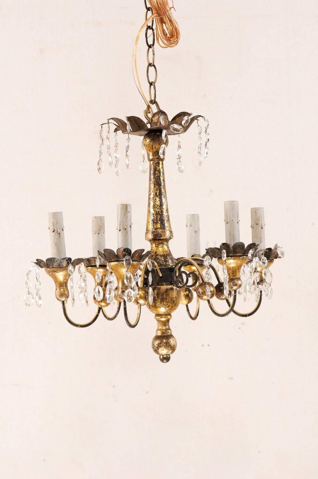 A pair of French six-light painted wood and crystal chandelier from the mid-20th century. This pair of vintage French chandeliers features a turned wood central column, with decoratively cut metal canopy adorn with crystals. From the centre column,