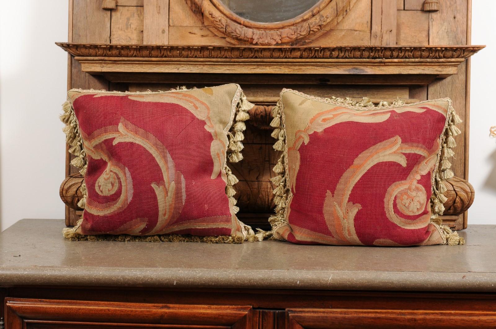 A pair of French pillows made from 19th century Aubusson tapestries, with scrolling foliage and tassels. Made from an exquisite tapestry created during the 19th century in the Aubusson Manufacture located in central France, each of this pair of