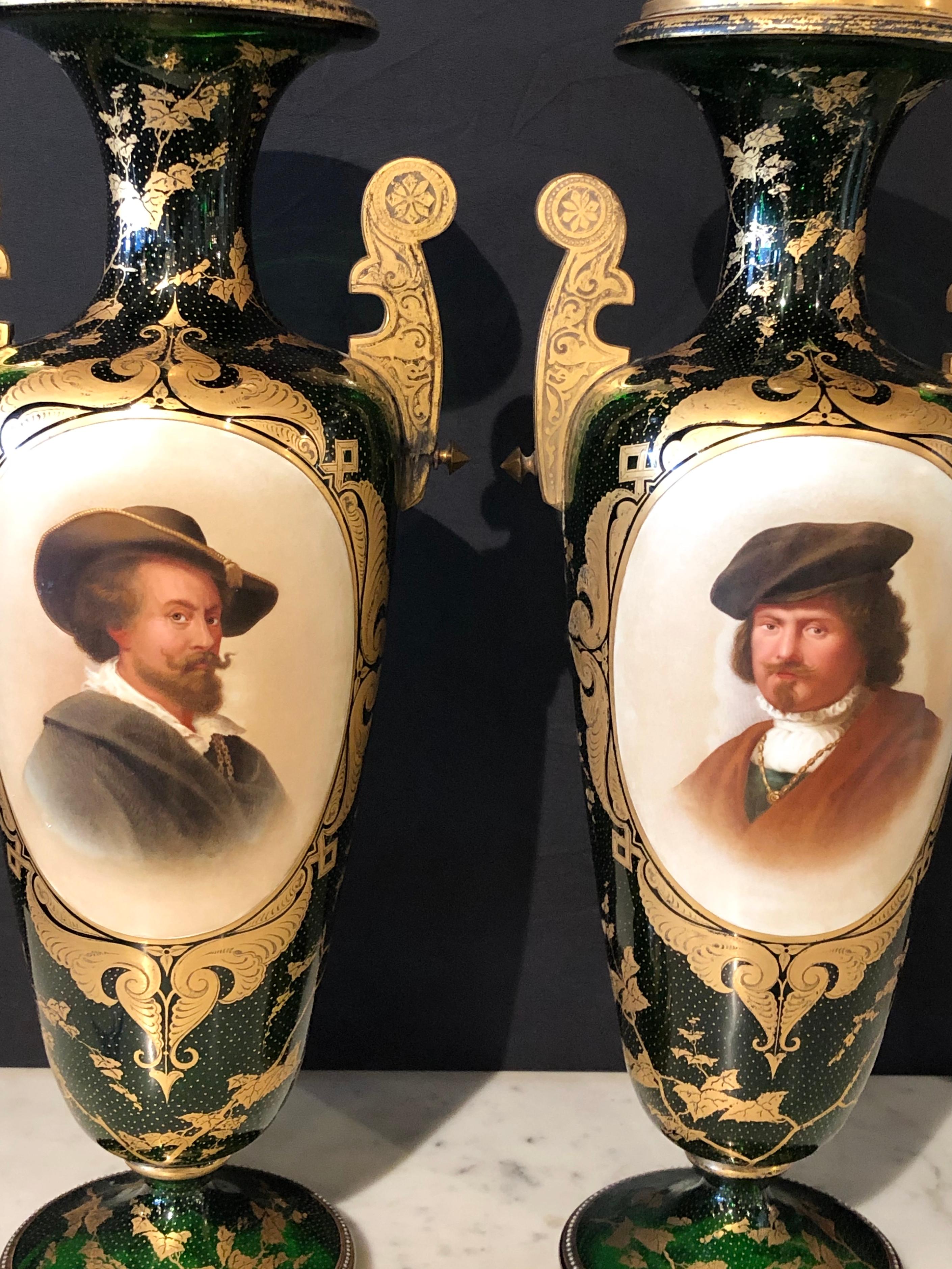 Pair of French portrait decorated green glass vases. This fine high stylized pair of decorated green glass vases have a gilt trim with portrait applied panels. The pair with gilt gold glass handles flanking finely painted portraits of two hatted
