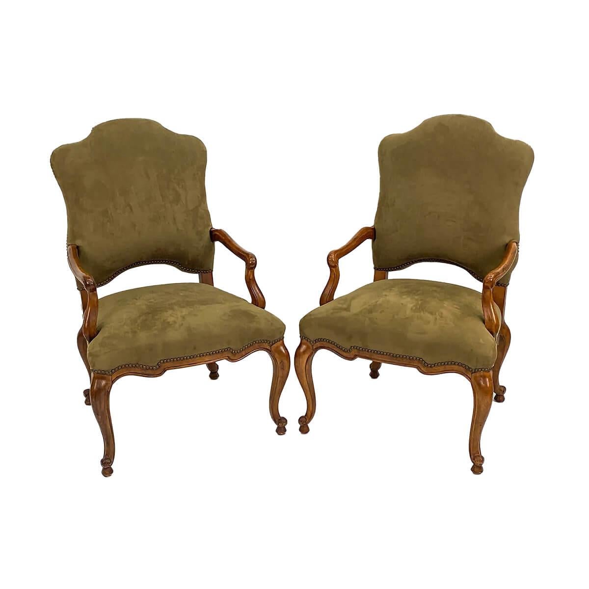 In the 18th century French Louis XV style. A large pair of carved Fauteuils with suede upholstered cushion backrest and seat. With a serpentine top rail and front, with brass nailhead details and raised on carved cabriole legs. France, Mid 20th