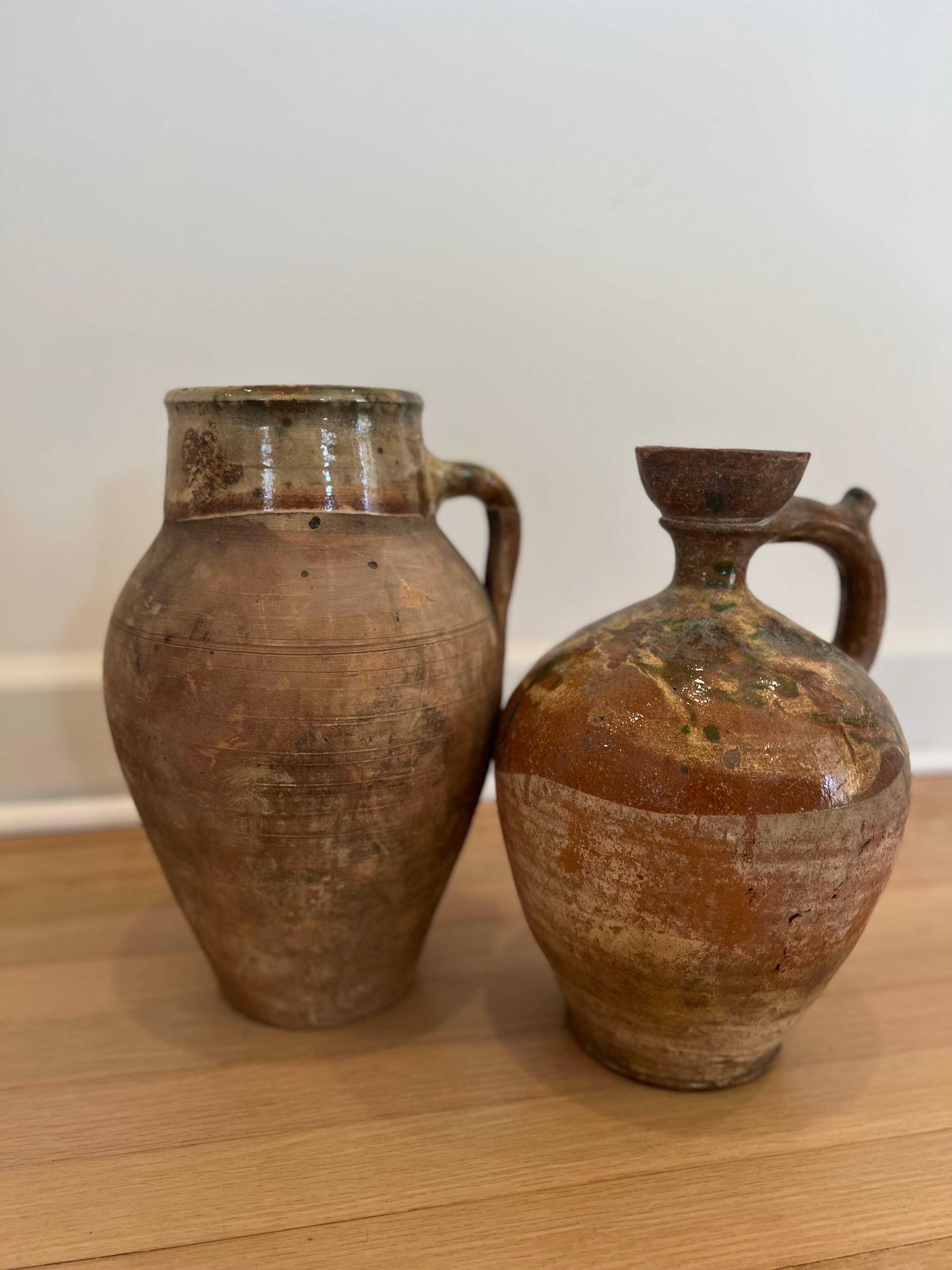 Paire de poteries Amphora anciennes de style provincial français.  L'un mesure environ 14 pouces de haut et l'autre environ 13 pouces de haut.

Couleurs et patine très similaires.   L'un d'eux semble avoir un bec verseur ébréché. 

Voir les images
