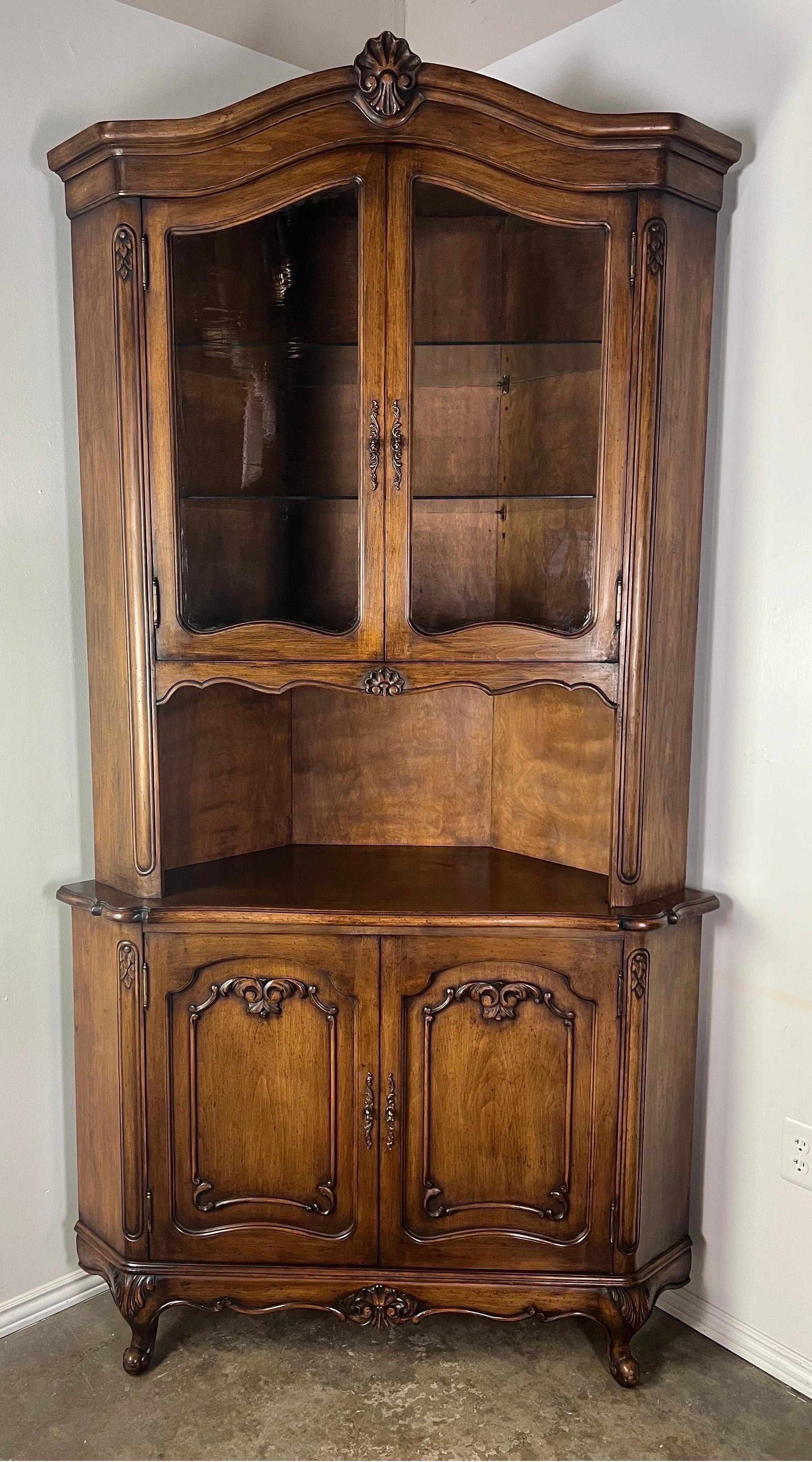 Pair of French Provincial walnut corner cabinets. There are two paneled doors on the bottom for plenty of storage. There are two glass doors on top to display your treasures.