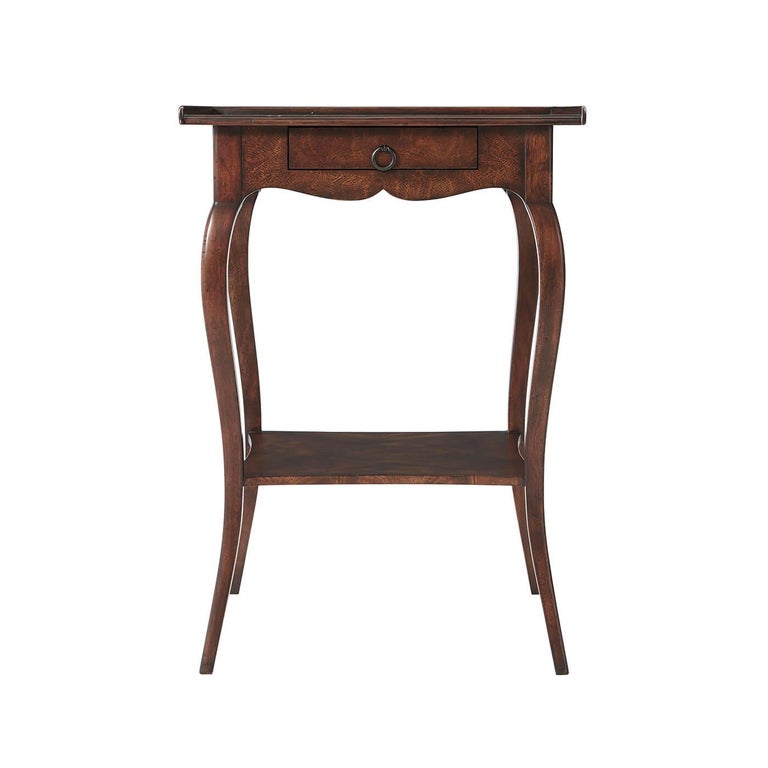 A French Provincial style end table, the square crossbanded top with a three-quarter gallery above an undulating apron fitted with a frieze drawer on cabriole legs joined by a concave sided under tier. Inspired by a French Louis XV style