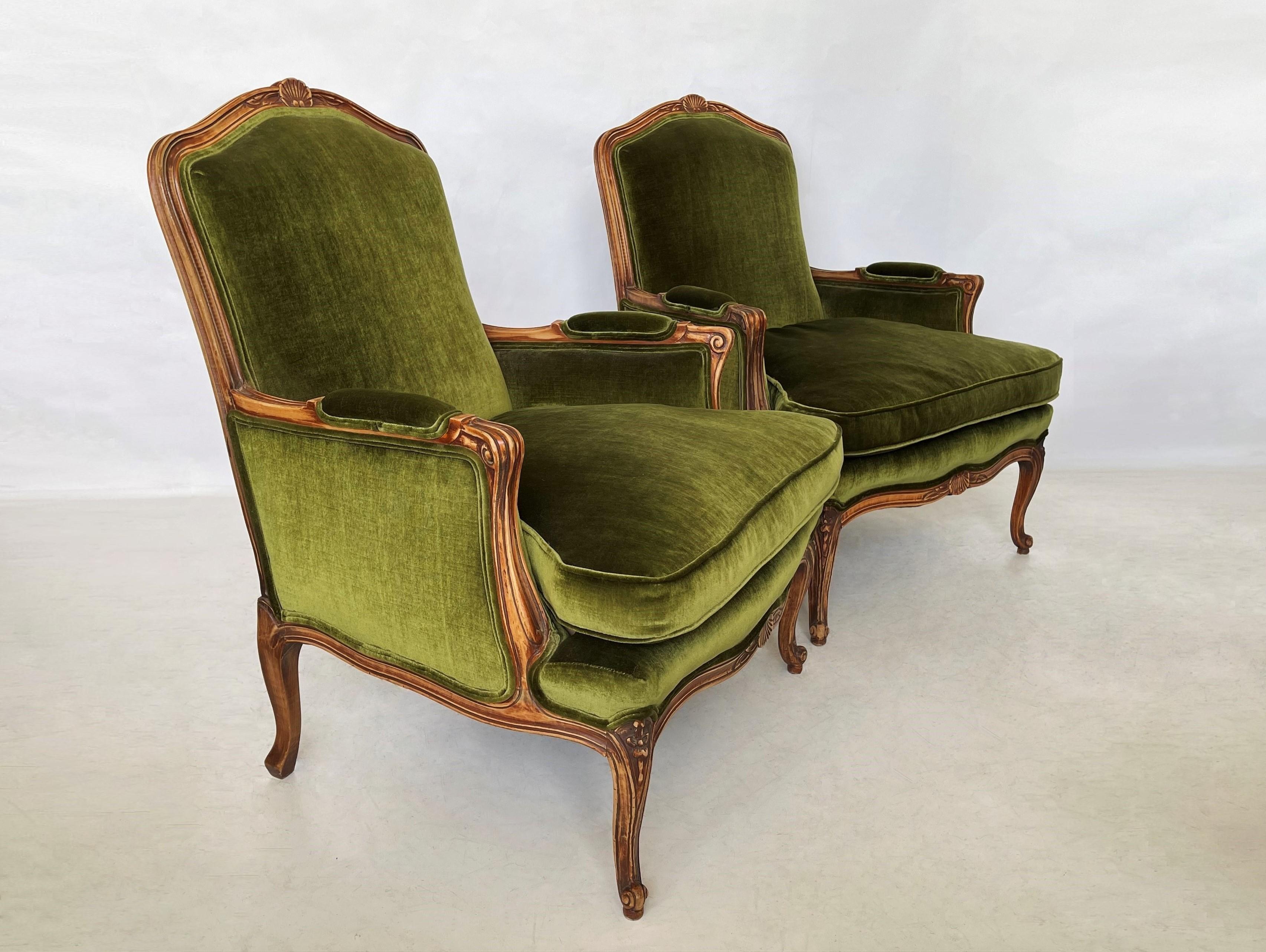 A lovely pair of carved French provincial Louis XV style bergères. Each with a cartouche-shape with carved cresting, padded back into down-swept out-scrolled padded arms over a cushion seat. Carved serpentine apron standing on four cabriole legs