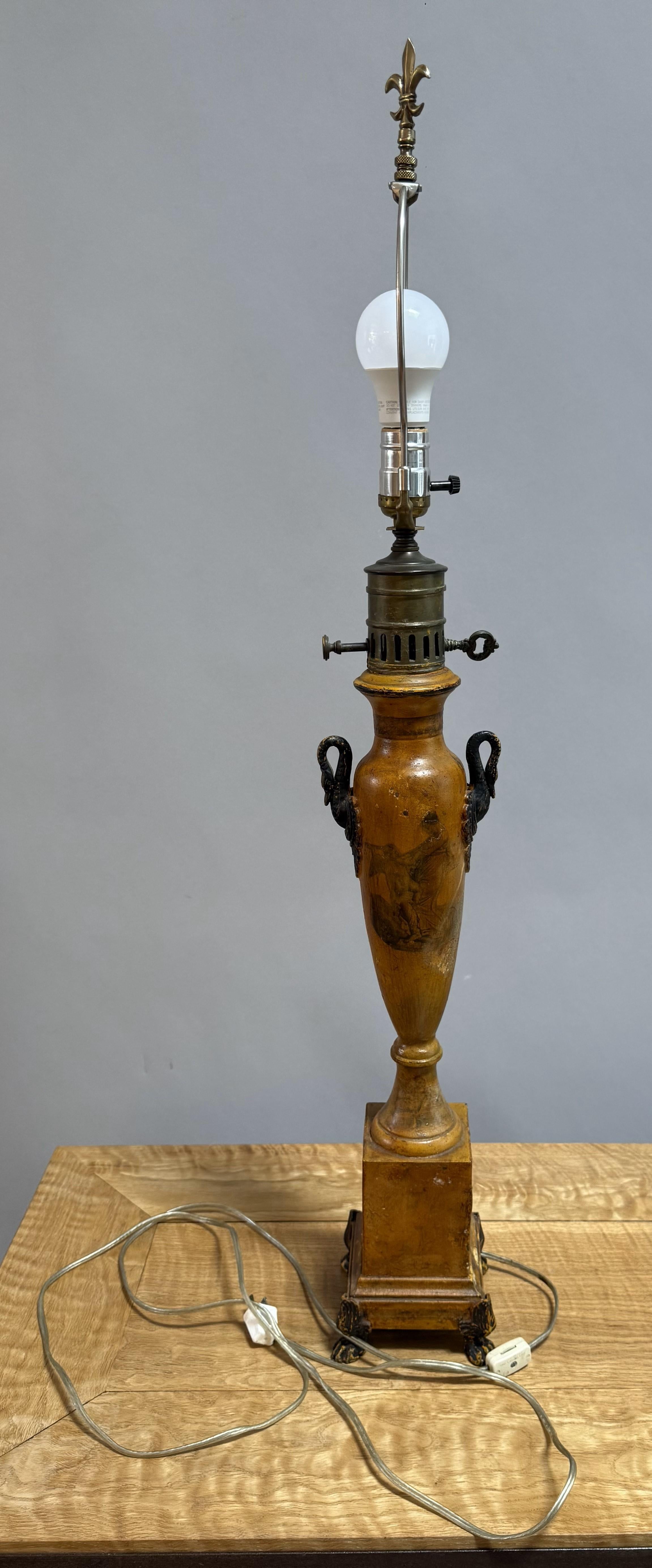 A graceful pair of French Provincial lamps, originally crafted as oil lamps in Provence circa 1800 and later expertly converted for electricity. Fashioned from painted tole, these urn-form bodies exemplify Neoclassical elegance with hand-painted