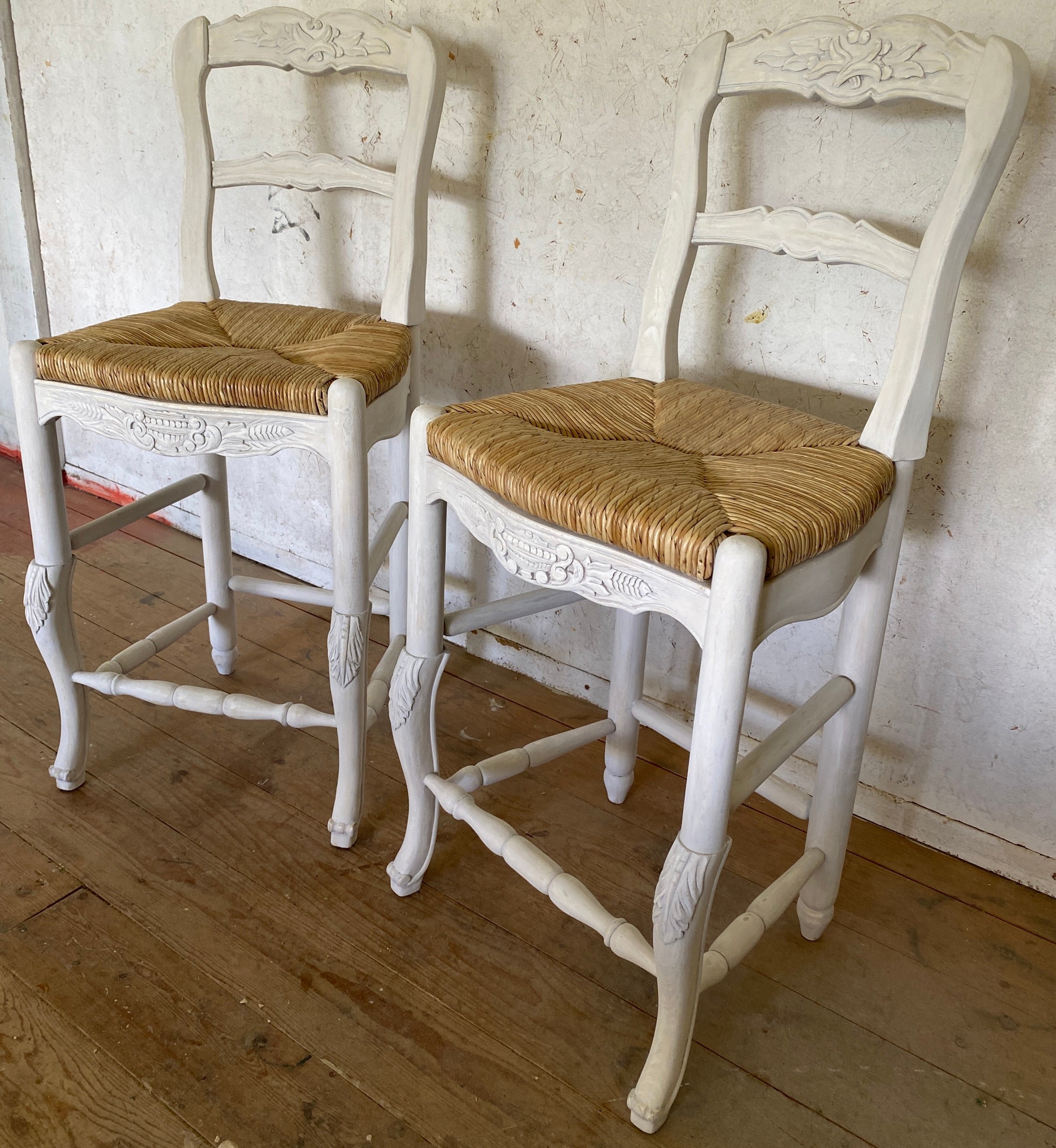 Pair of French Louis XV Provincial style carved wooden bar stools with rushed seats and cabriole style front legs.