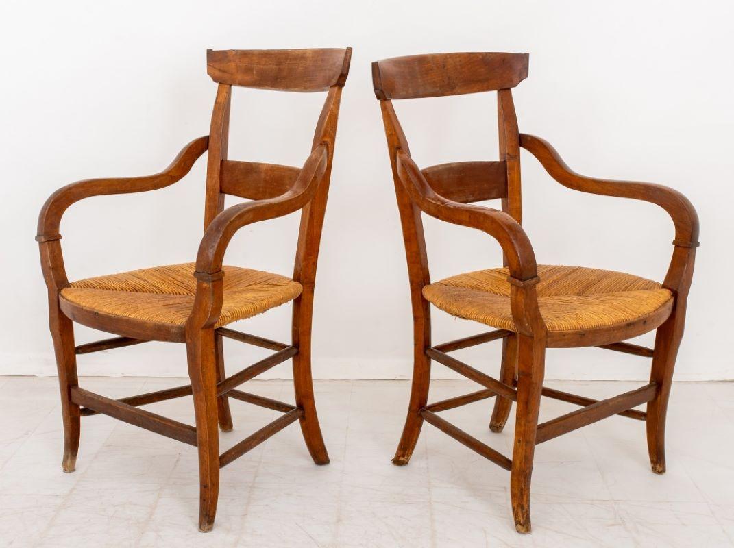 Pair of French Provincial Style Walnut Rush Seat Armchairs, 19th century, conjoined by two-tiered stretchers on four tapered legs. 34.5
