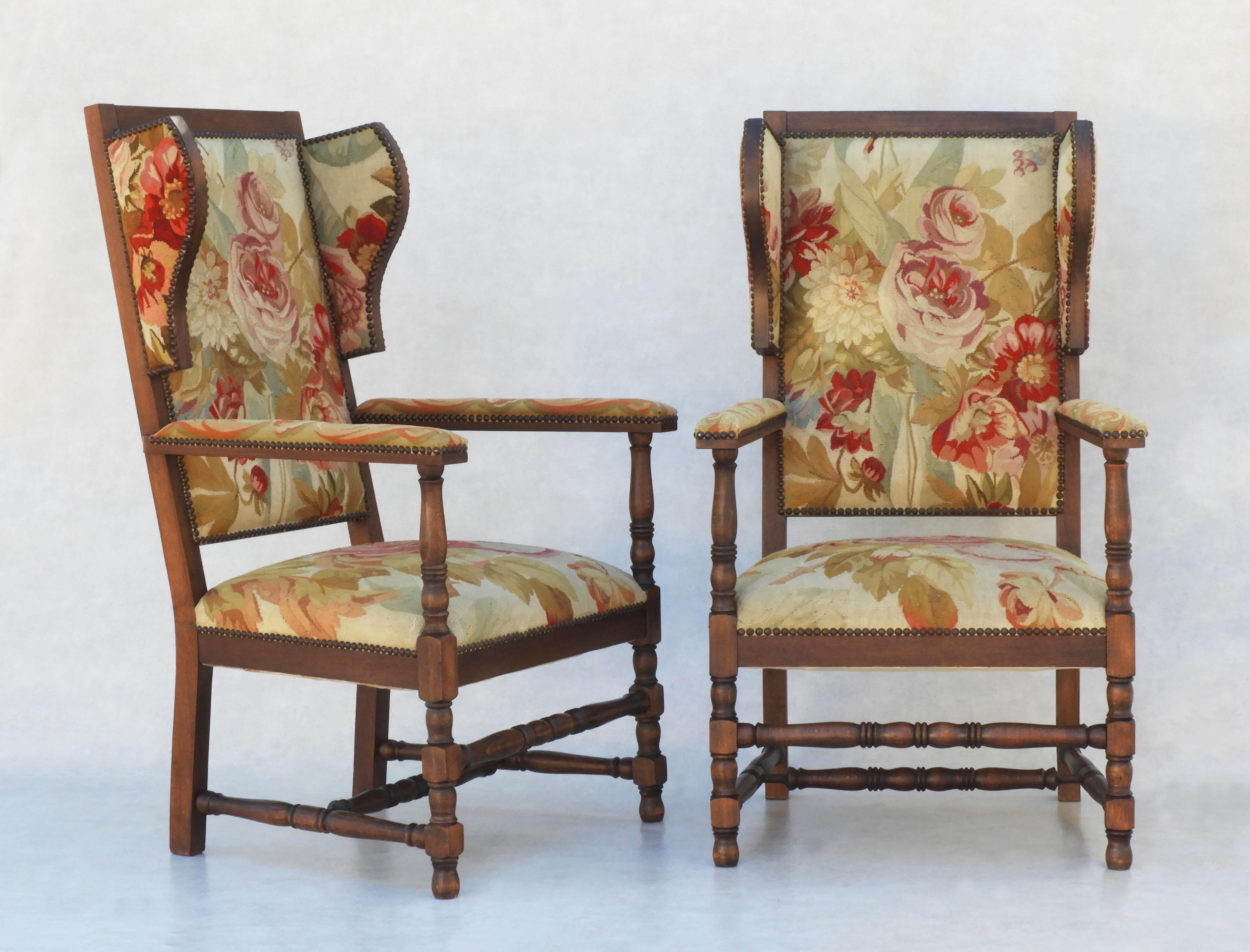 Charming pair of Provincial French wingback chairs. An unusual duo of oak-framed armchairs upholstered in a striking rose-themed floral tapestry. All original and thought to be a totally unique pair. In good vintage condition, comfortable, sturdy