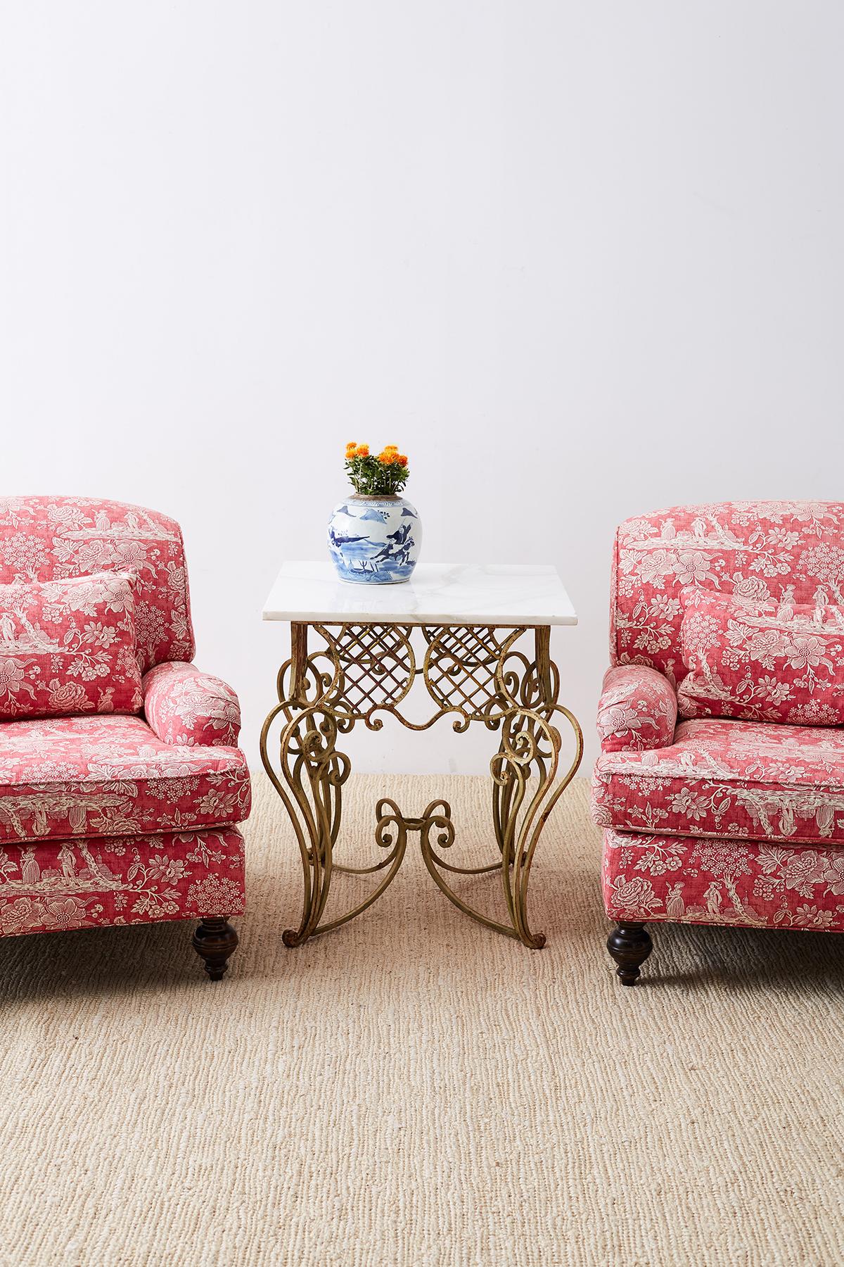 Fabulous pair of French Provincial toile oversized lounge chairs upholstered in a chinoiserie red toile de jouy printed fabric. Constructed with large heavy mahogany frames featuring an English rolled arm and a deep seat cushion. Very comfortable