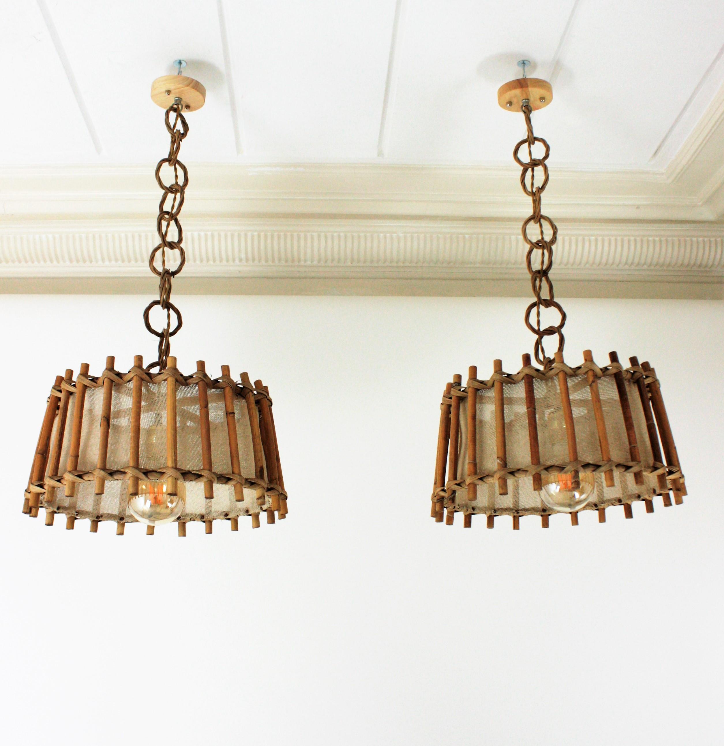 Beautiful pair of rattan and wicker round pendants with burlap sack interior shades. France, 1960s
These suspension lamps or lanterns feature an slightly conical round lampshade made of thick rattan canes. The interior part is upholstered with