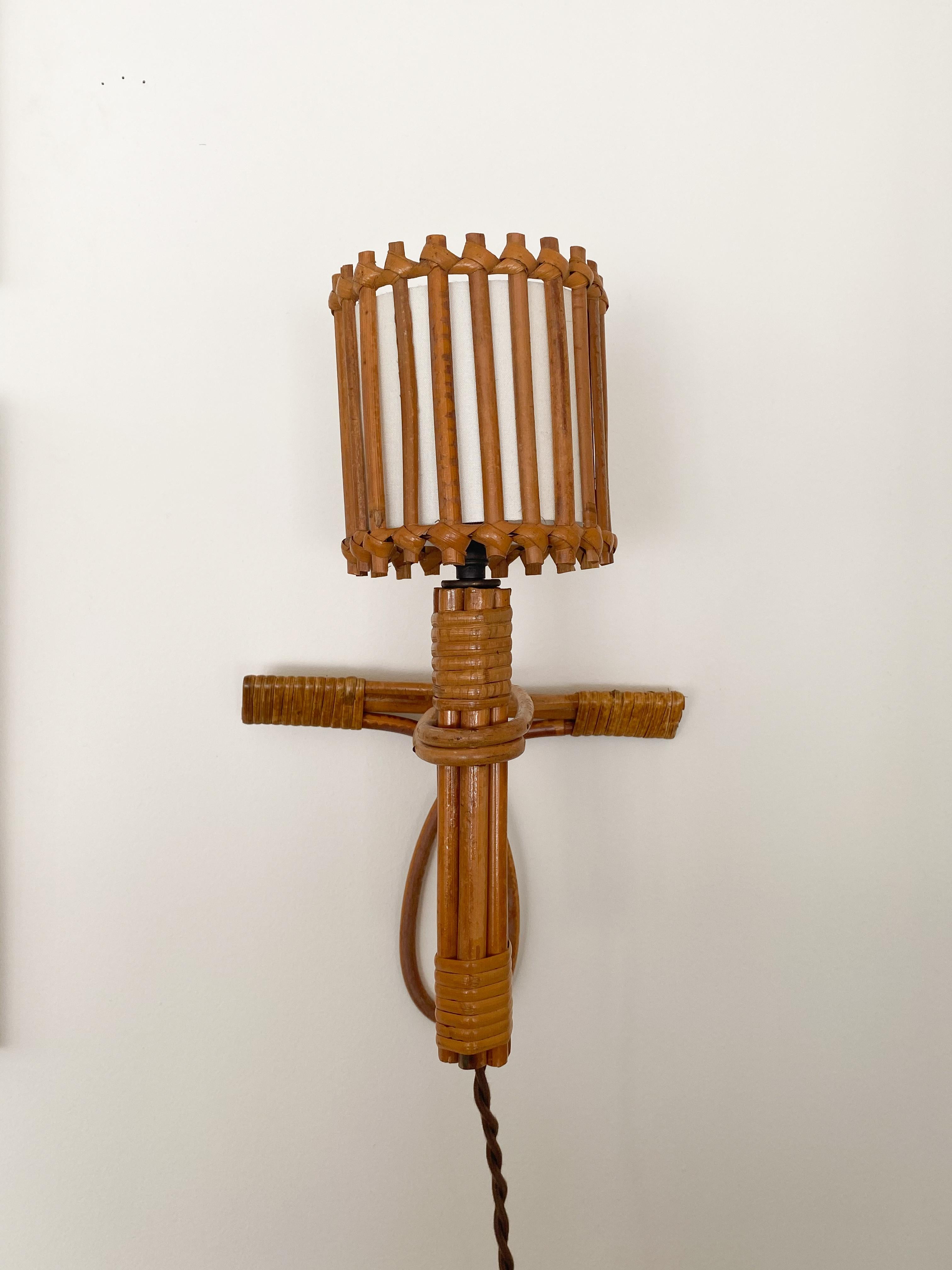 Vintage pair of Louis Sognot rattan sconces from France, 1960s. Rattan torch shape with single bulb in each. Newly re-wired with brown cloth twist cord and new plug. Original rattan finish, silk interior shade with some light markings.