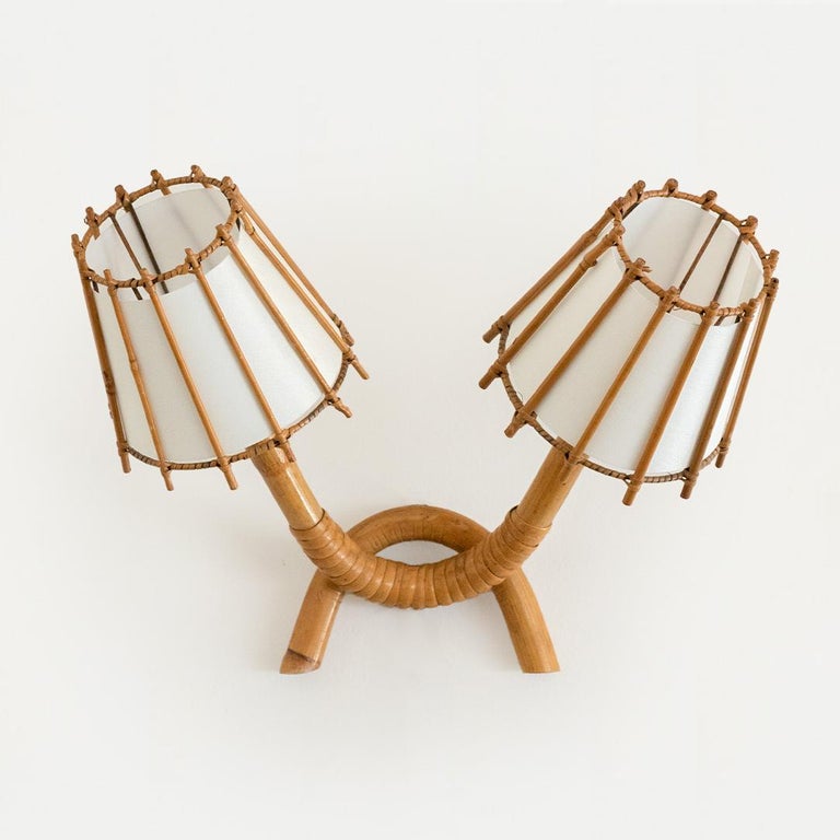 Vintage rattan sconce by Louis Sognot from France, 1960s. Two bamboo arms in V shape with rattan shades and new interior silk lining. Newly re-wired with brown cloth twist cord and new plug. Original rattan finish with nice age and patina. Sconce