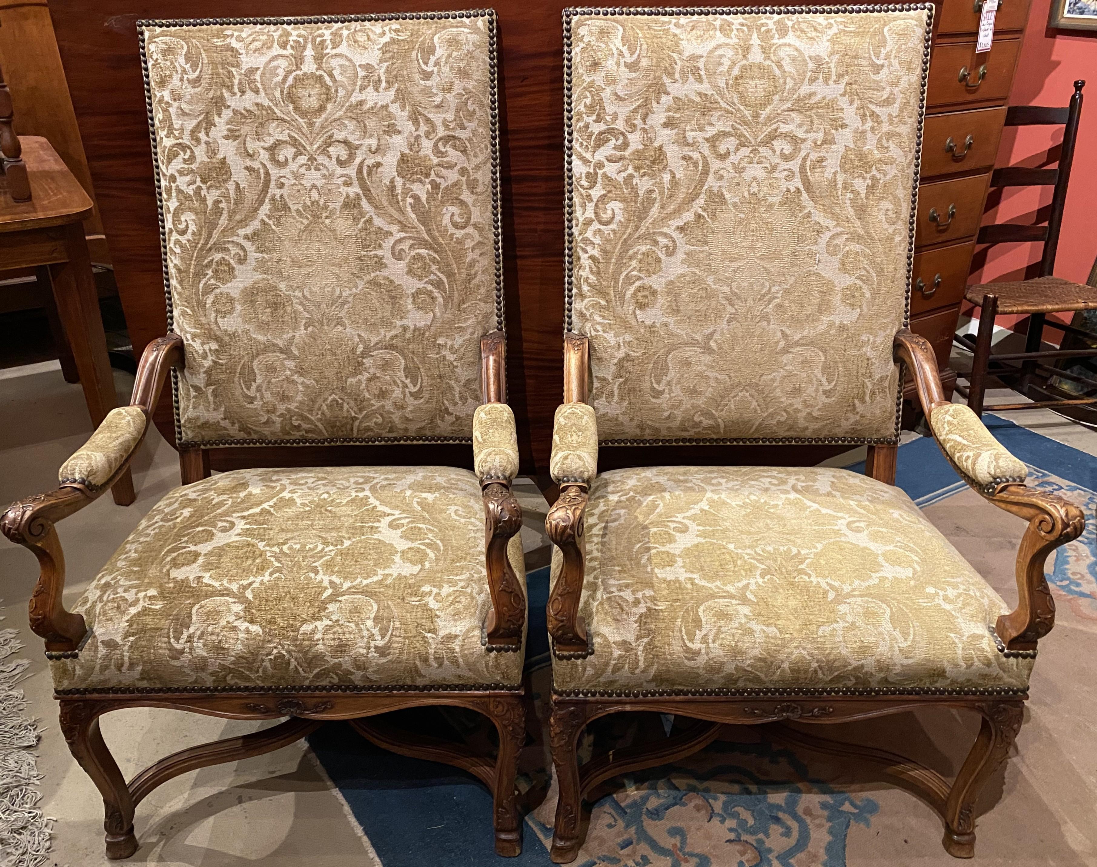 Coppia di poltrone con schienale alto in noce intagliato in stile Regence francese o fauteuils con imbottitura foliata, finitura con chiodi e decorazione foliata intagliata sui braccioli sagomati. La coppia presenta anche una gonna smerlata, gambe