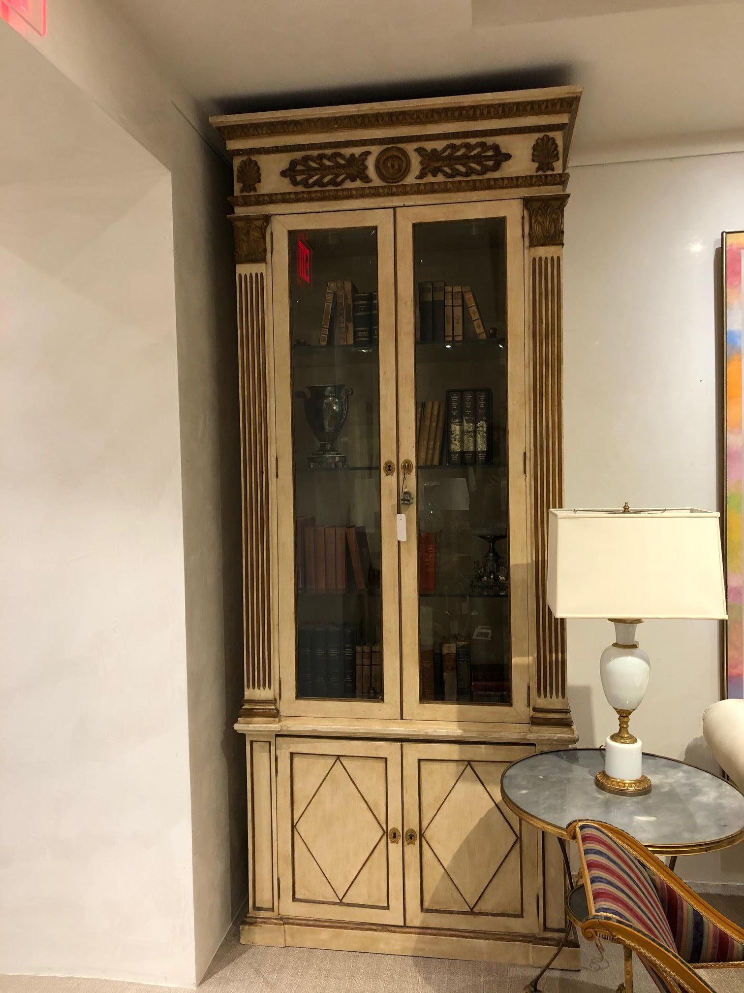 Pair of French Regence-style cream painted and gilt trimmed bookcase cabinets with 2 glass front doors with gilt pilaster column sides above 2 lower doors with a diamond design. (PRICED AS Pair).
 