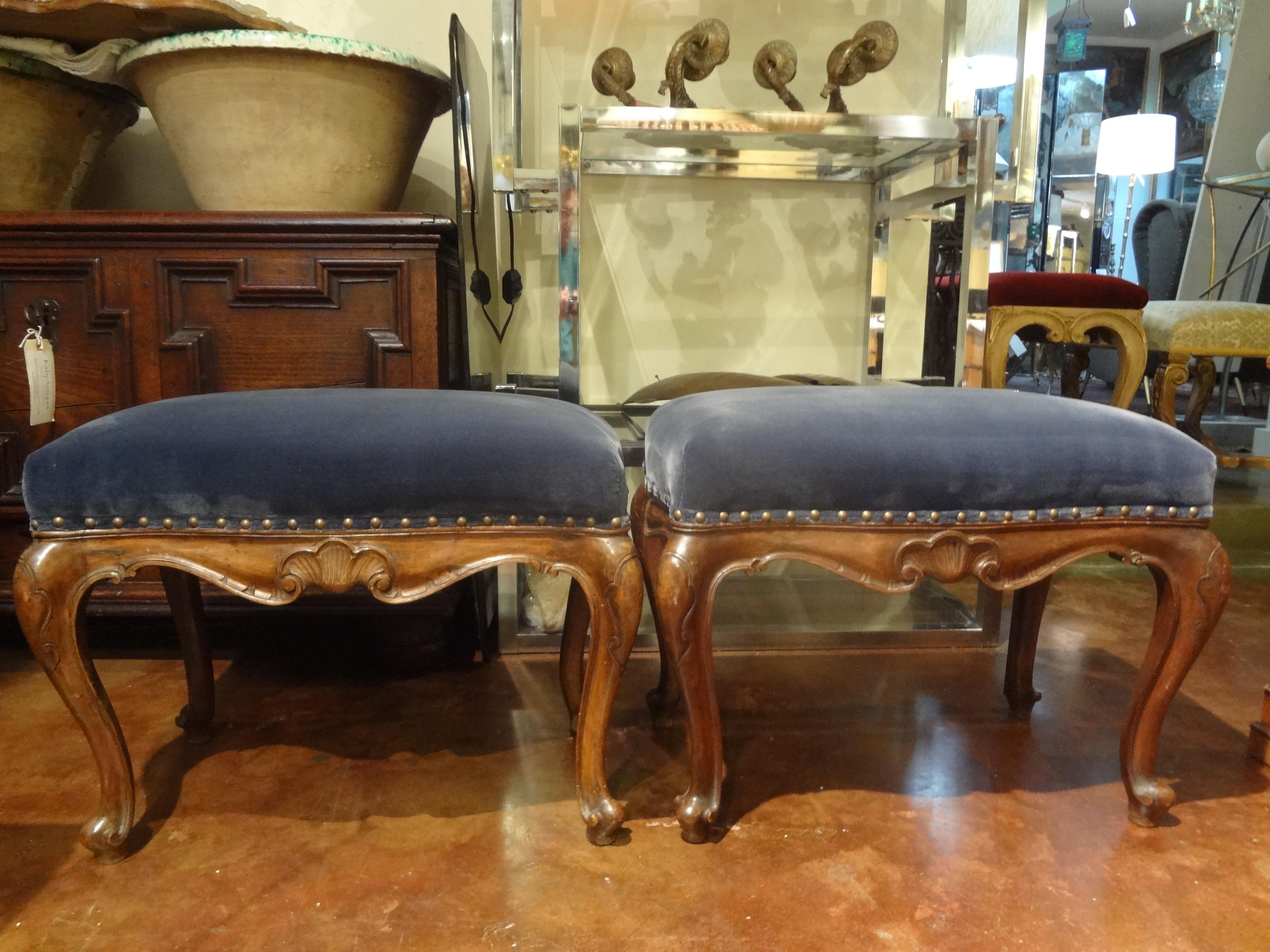 Fantastic pair of antique Italian Regence style walnut benches, stools or ottomans. This pair of French benches have been newly upholstered in a gorgeous shade of blue velvet with spaced nailhead detail. Form and function in this pair of usable
