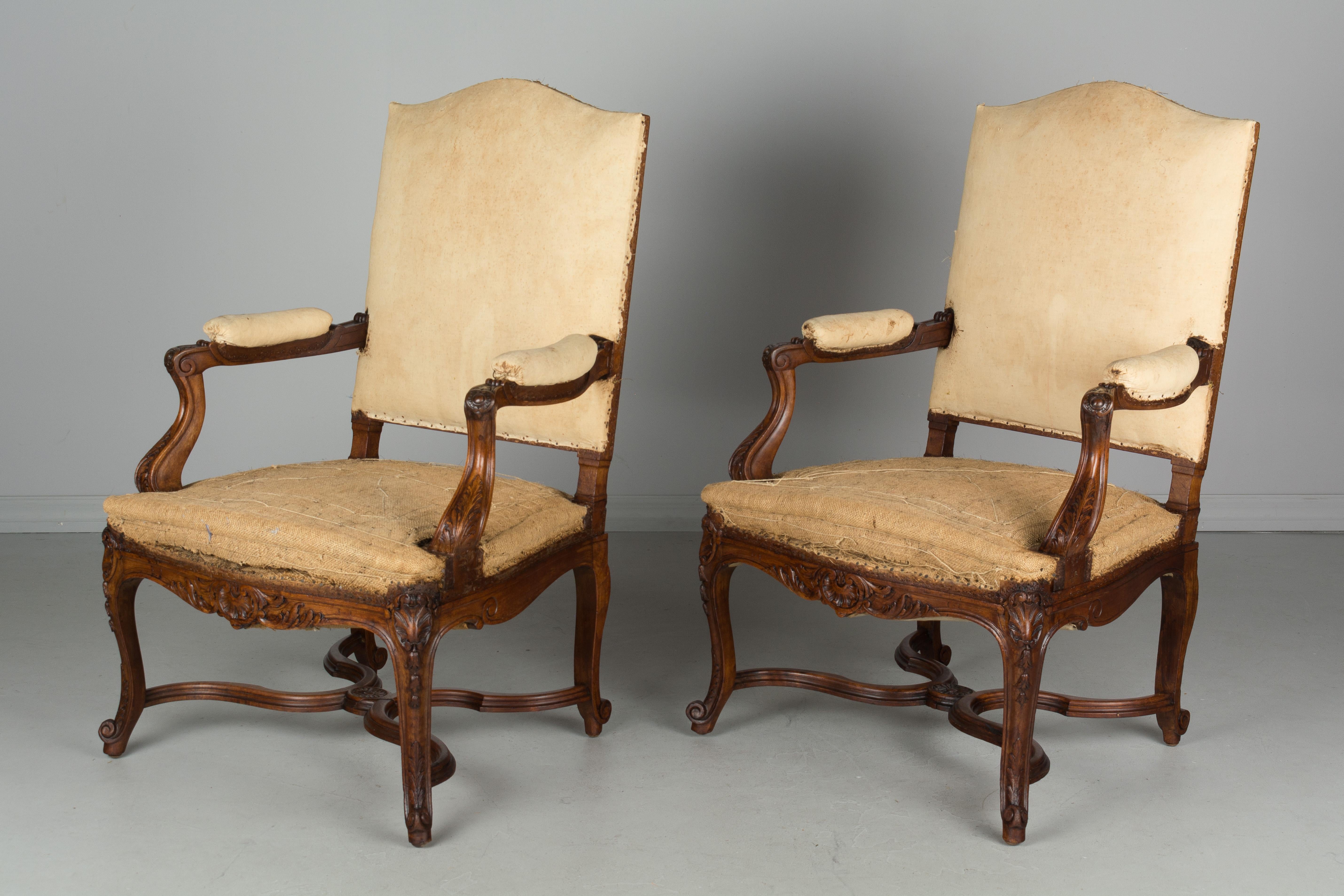 Pair of French Regence style fauteuils, or arm chairs. Hand-carved walnut frames with X-stretcher. Sturdy with comfortable proportions. Stripped of old fabric and sold as is.
  