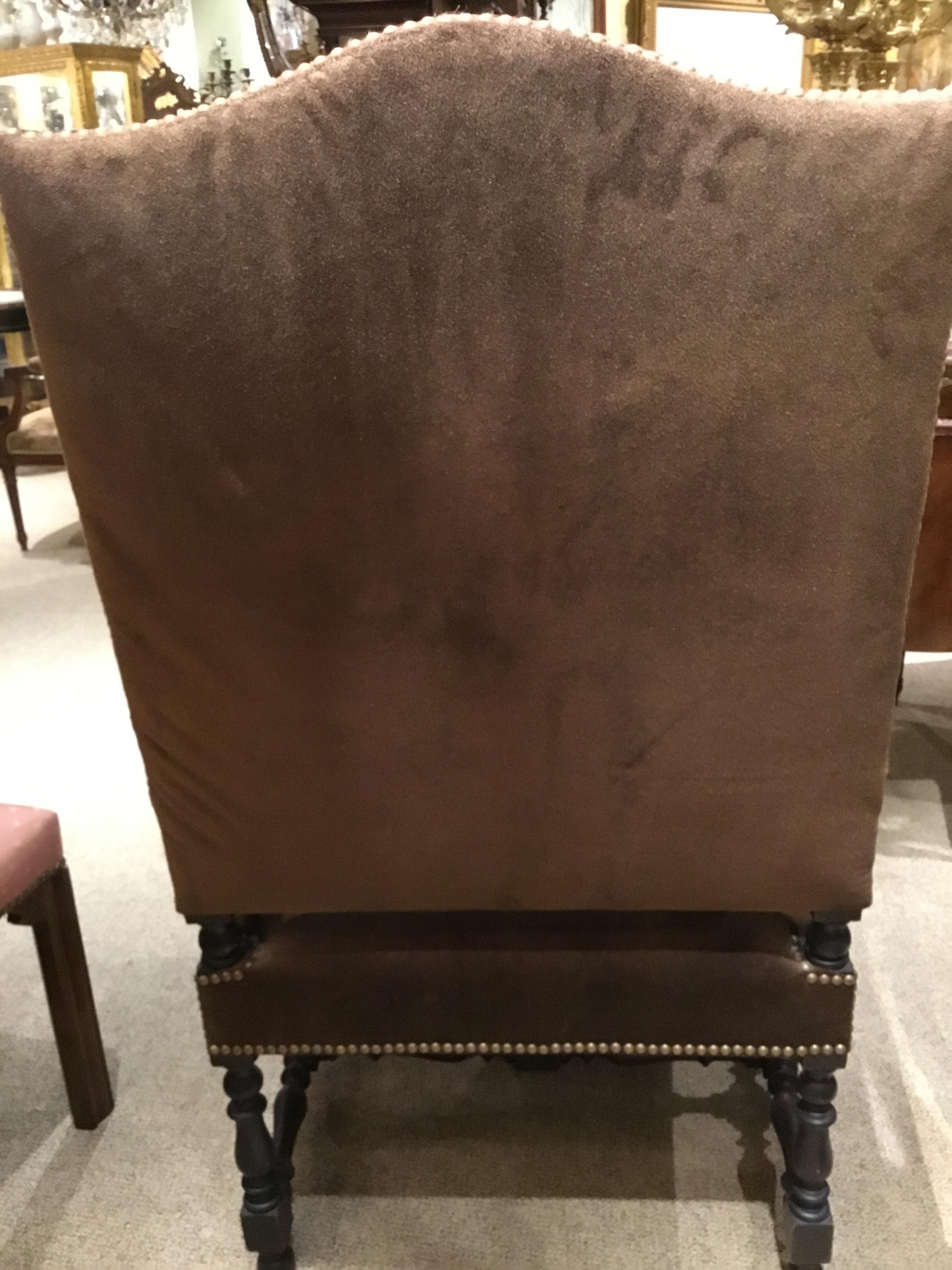 Handsome pair of tall back chairs with cow hide upholstery. Carved arms with roll design, stretchers 
On the legs on both the front and the center bottom. Nailhead trim.