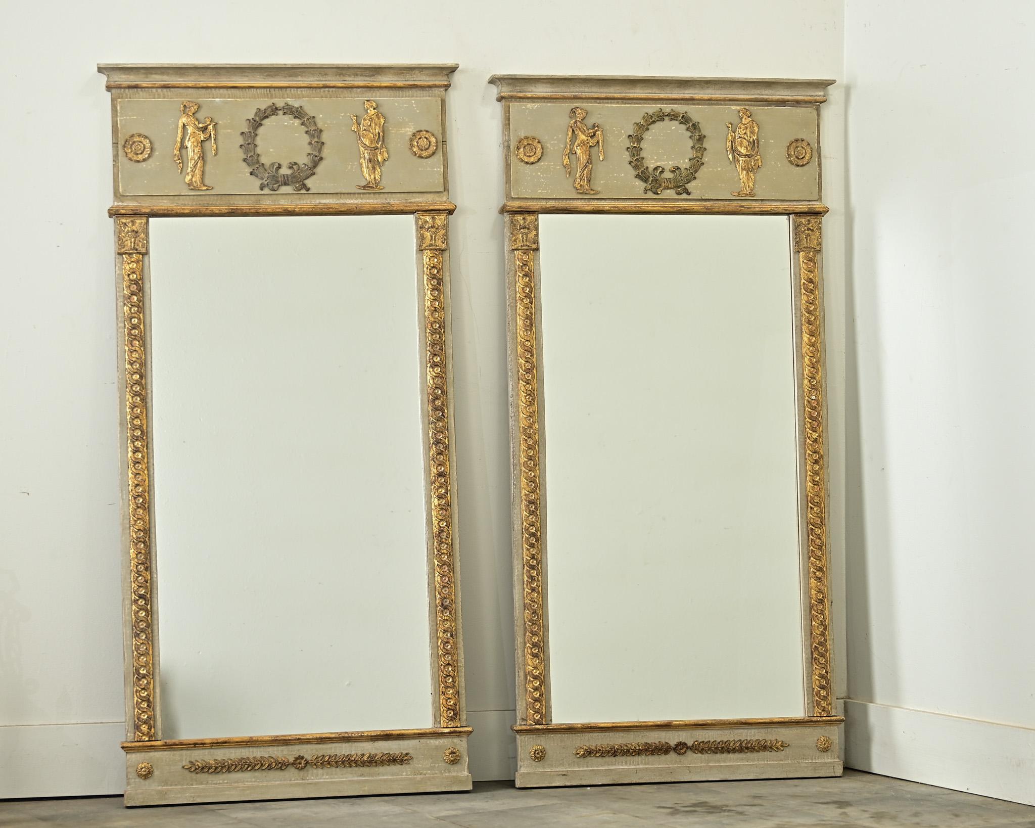 Une superbe paire de miroirs trumeau de style Empire français avec des motifs néoclassiques décorant les cadres peints en gris-vert pour une esthétique sophistiquée et intemporelle, quels que soient les goûts en matière de décoration. Dans la frise,