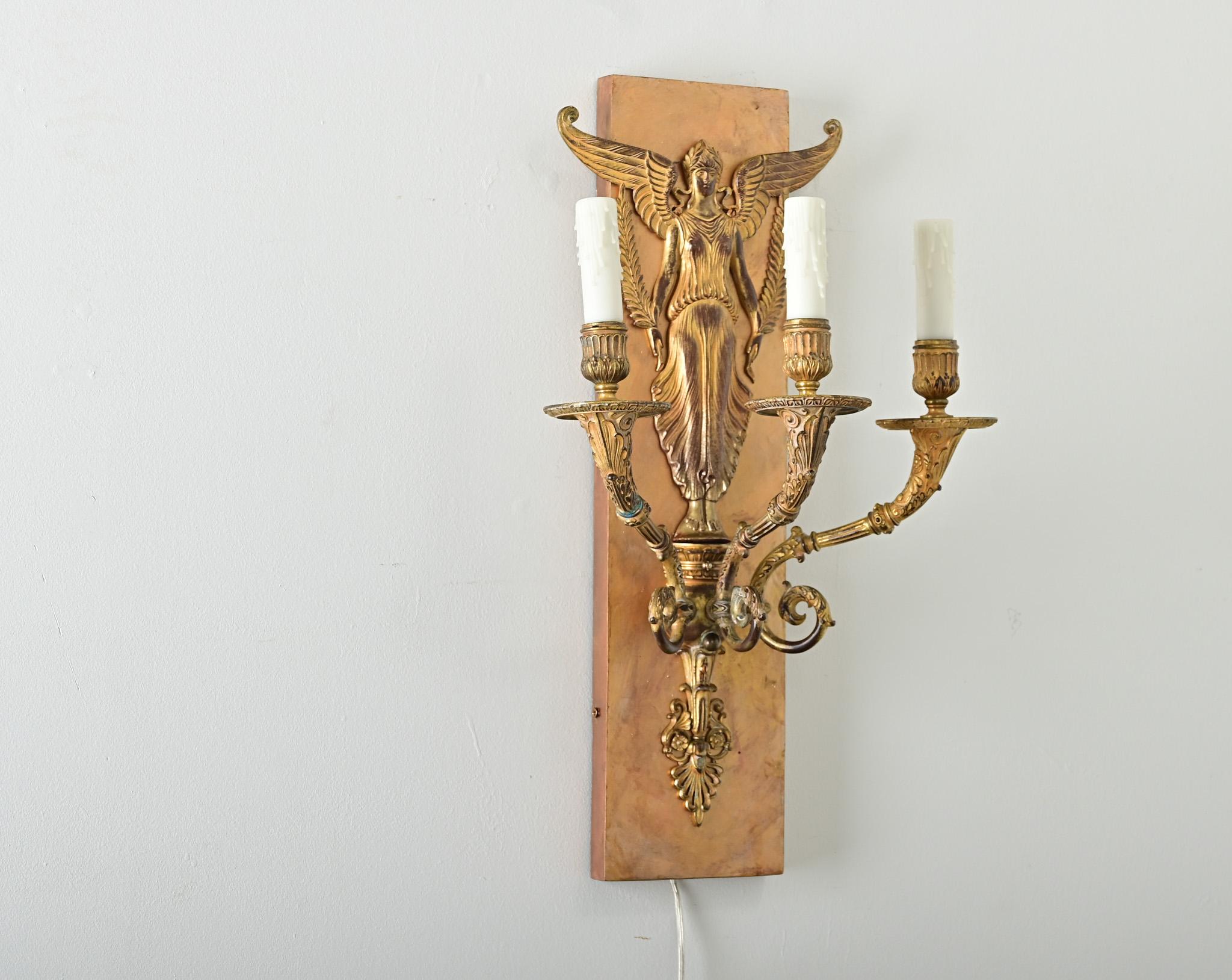 An absolutely dazzling and heavy gilt bronze wall sconces from the French Restauration period (19th century), capturing all the splendor and opulence of Neoclassical taste since the First Empire. The winged, caryatid-like figure standing above the