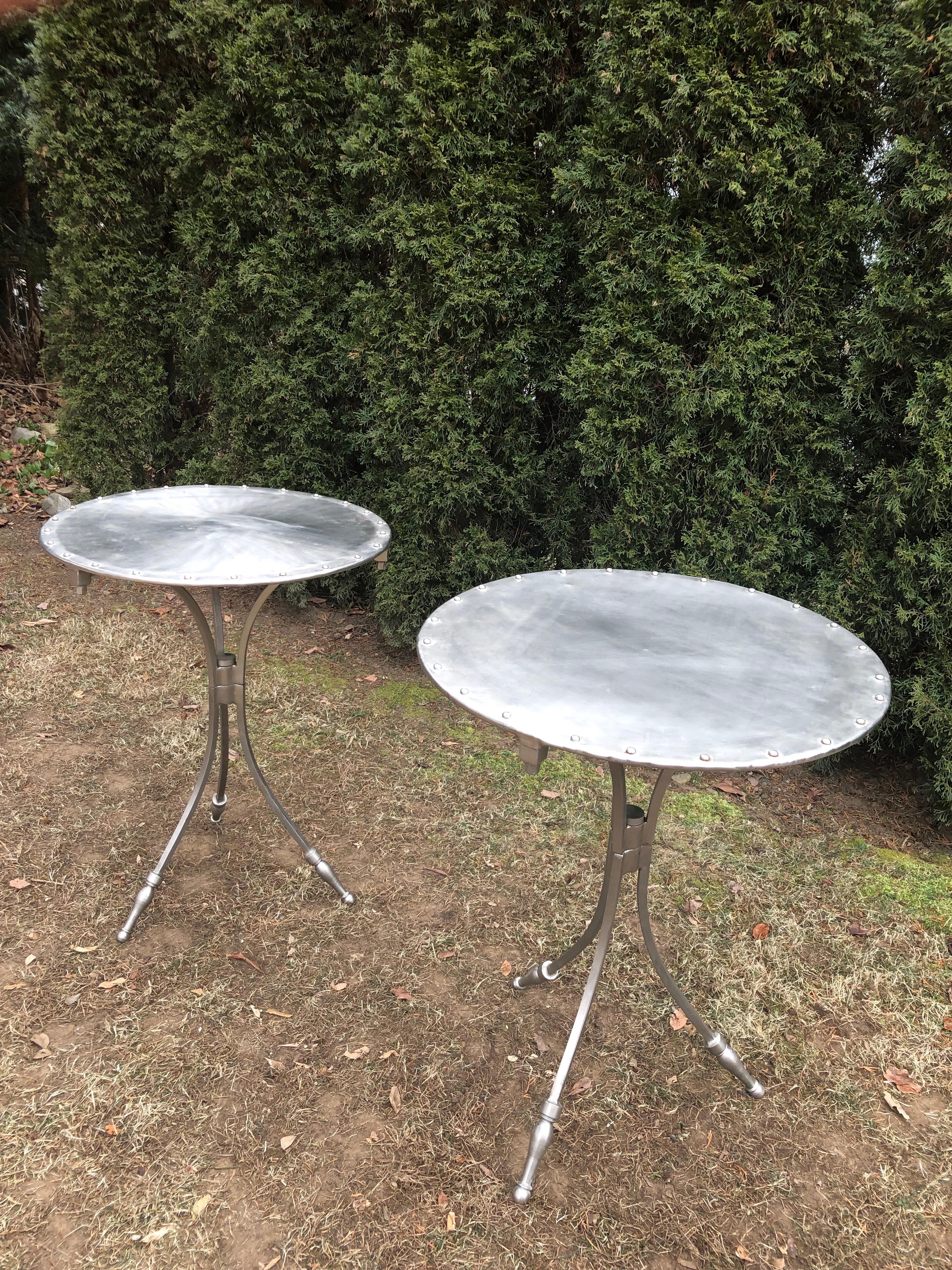Breathtaking in form and construction, this pair of French “gueridons” feature round riveted tops, a trio of splayed legs, and great detailing on the feet, stem and underside edges. In overall very good vintage condition, they each have a few small