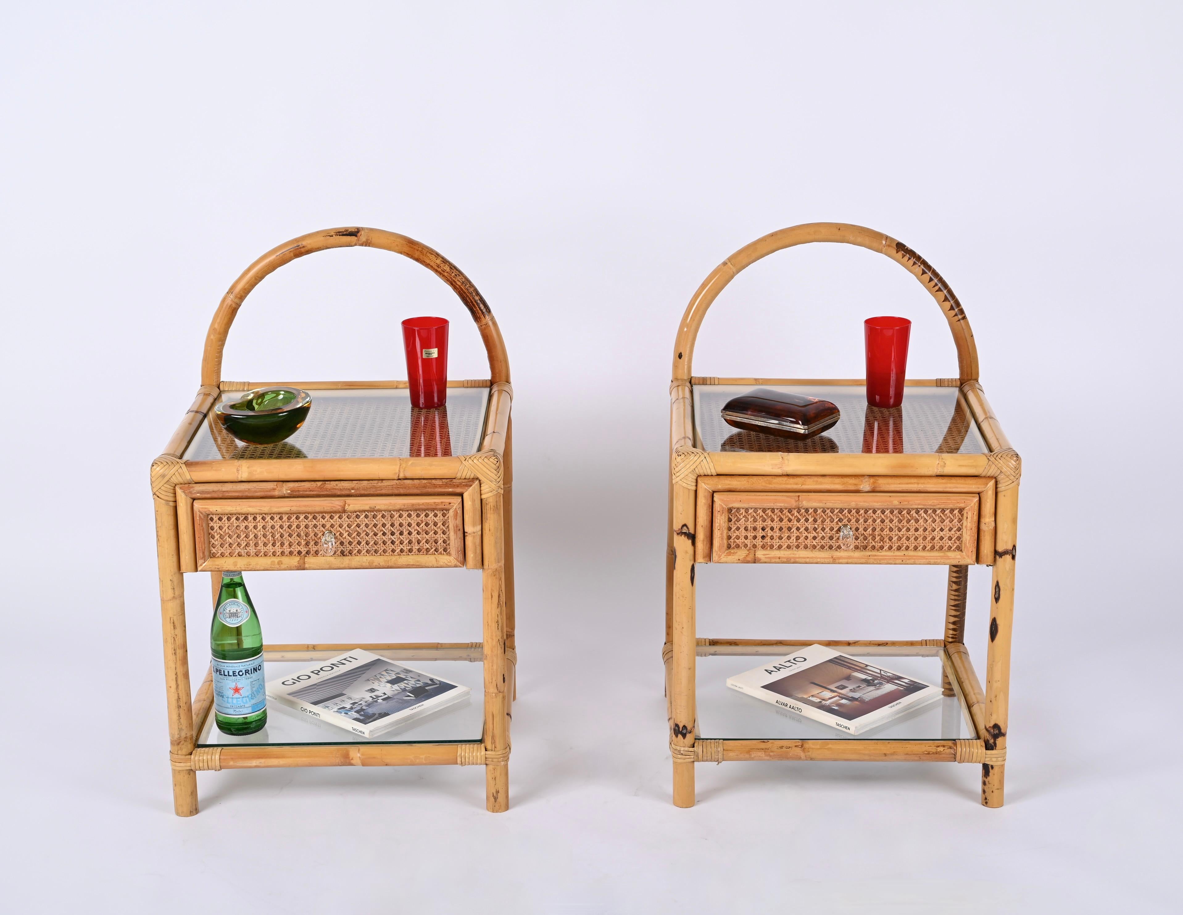 Fantastic pair of Mid-Century nightstands in bamboo, Vienna straw, hand-woven rattan wicker and clear glass. These lovely French Riviera style bedside tables were designed in Italy during the 1970s.

These charming organic nightstands are fully made