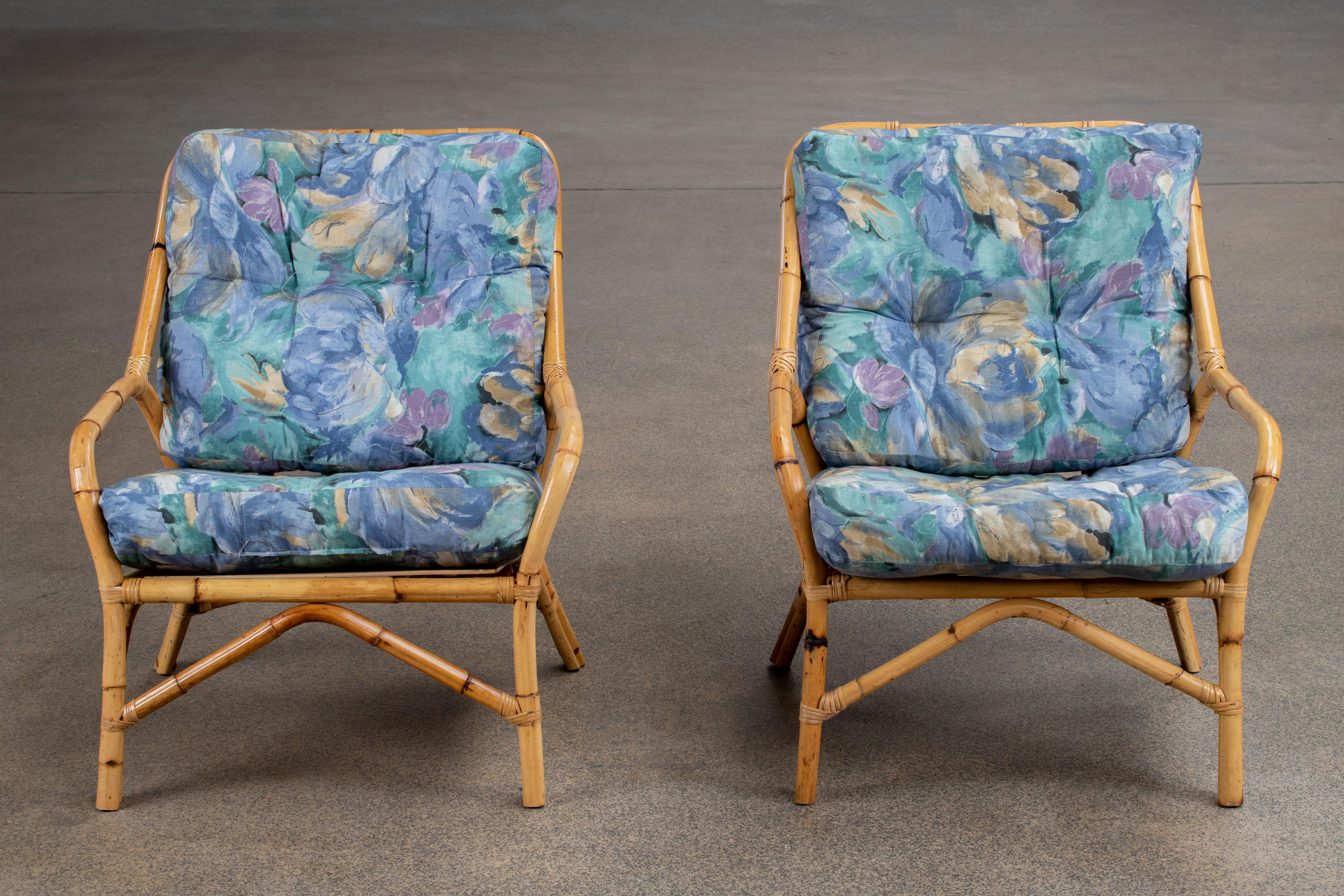 Gorgeous pair of 1970s oversized bamboo rattan lounge chairs made in the French Riviera organic modern style. The chairs feature a large bent rattan frame fitted with Silky blue cushions. Very comfortable with excellent joinery and craftsmanship.