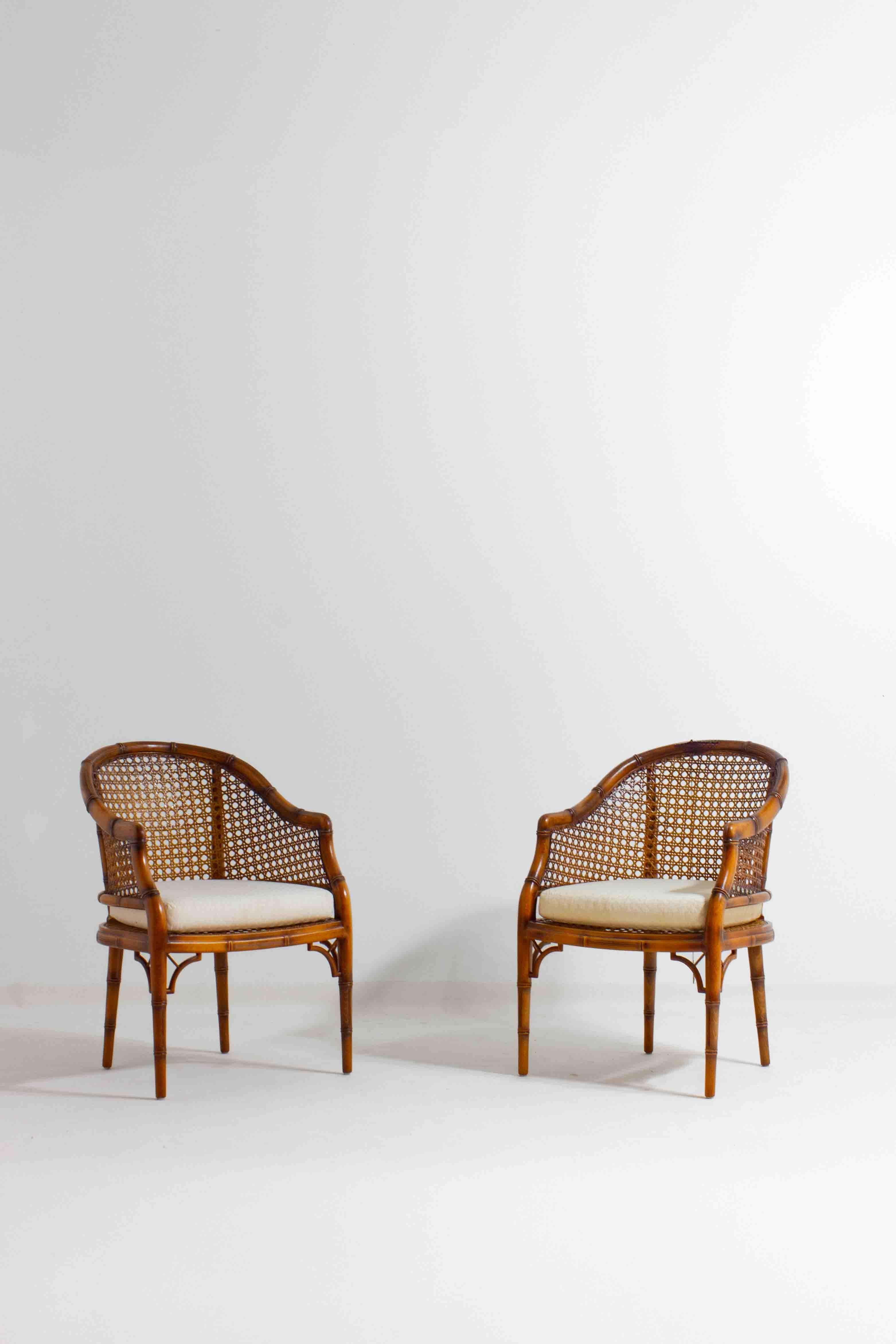 Lovely set of two faux bamboo French riviera style lounge chairs. The wooden frame and curved back- and armrests, made from woven cane and wicker are in absolute splendid condition.