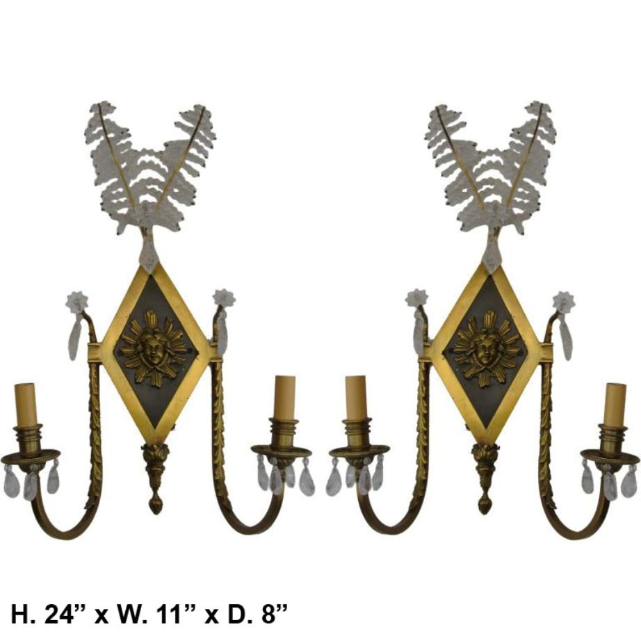 Bella coppia di appliques a due luci in stile neoclassico francese in cristallo di rocca e bronzo dorato. (A)
Ogni applique è sormontata da due foglie con perline di cristallo, sopra una piastra posteriore a forma di diamante in bronzo dorato e