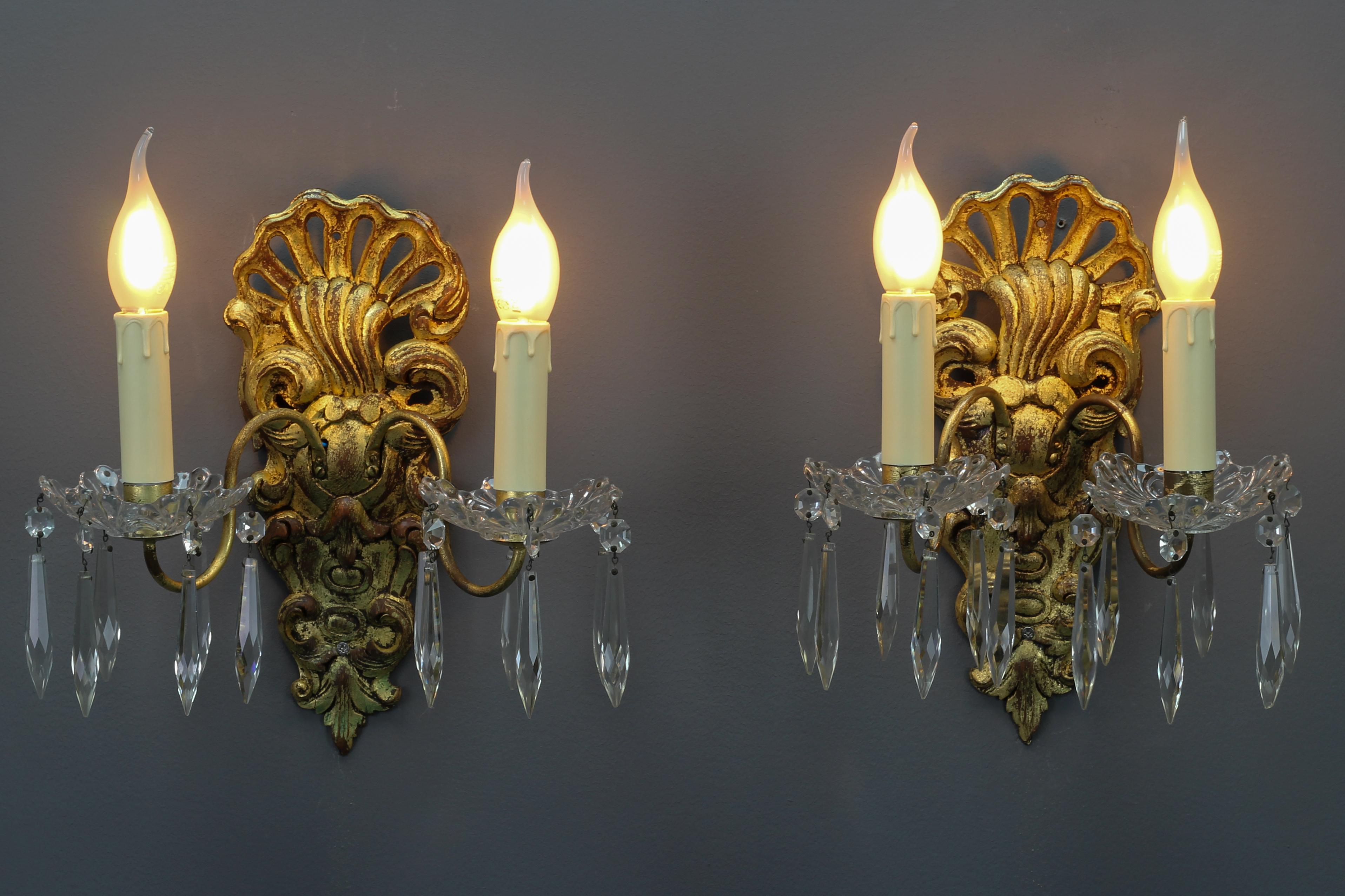 Pair of French Rococo style carved giltwood and crystal glass sconces.
A pair of ornate French Rococo-style carved and gilt wood sconces from the early 20th century. Sconces have been electrified later, have glass bobeches, and are ornate with