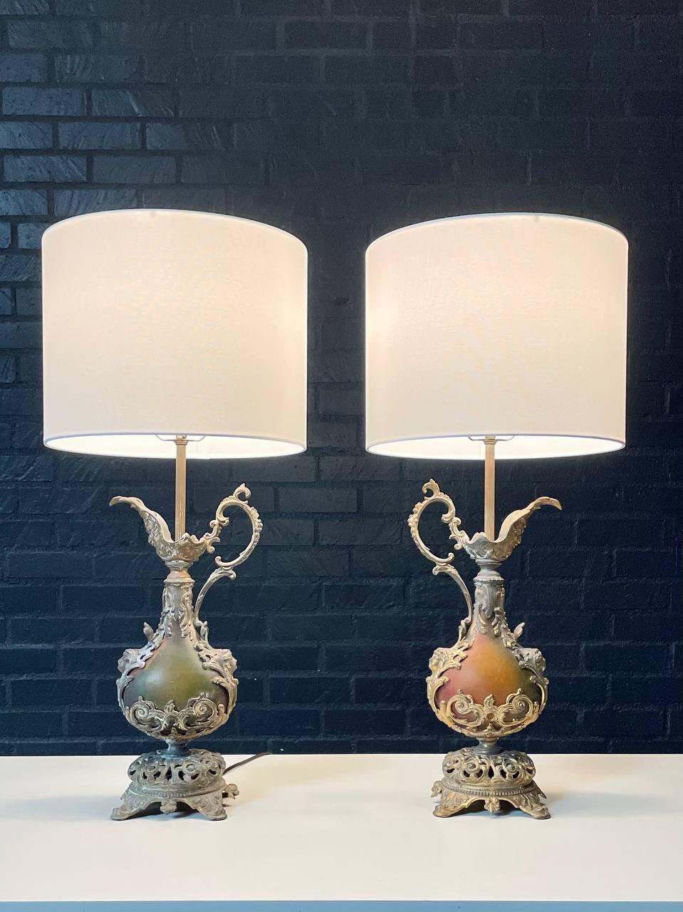 Condition: Newly Rewired, New Linen Shades
Materials: Spelter Metal w/ Brass Plated, Lacquered Metal
Style: French Rococo 

This striking pair of French Rococo style table lamps, c.1930s, brings the grandeur of the Old World into the New. Crafted in