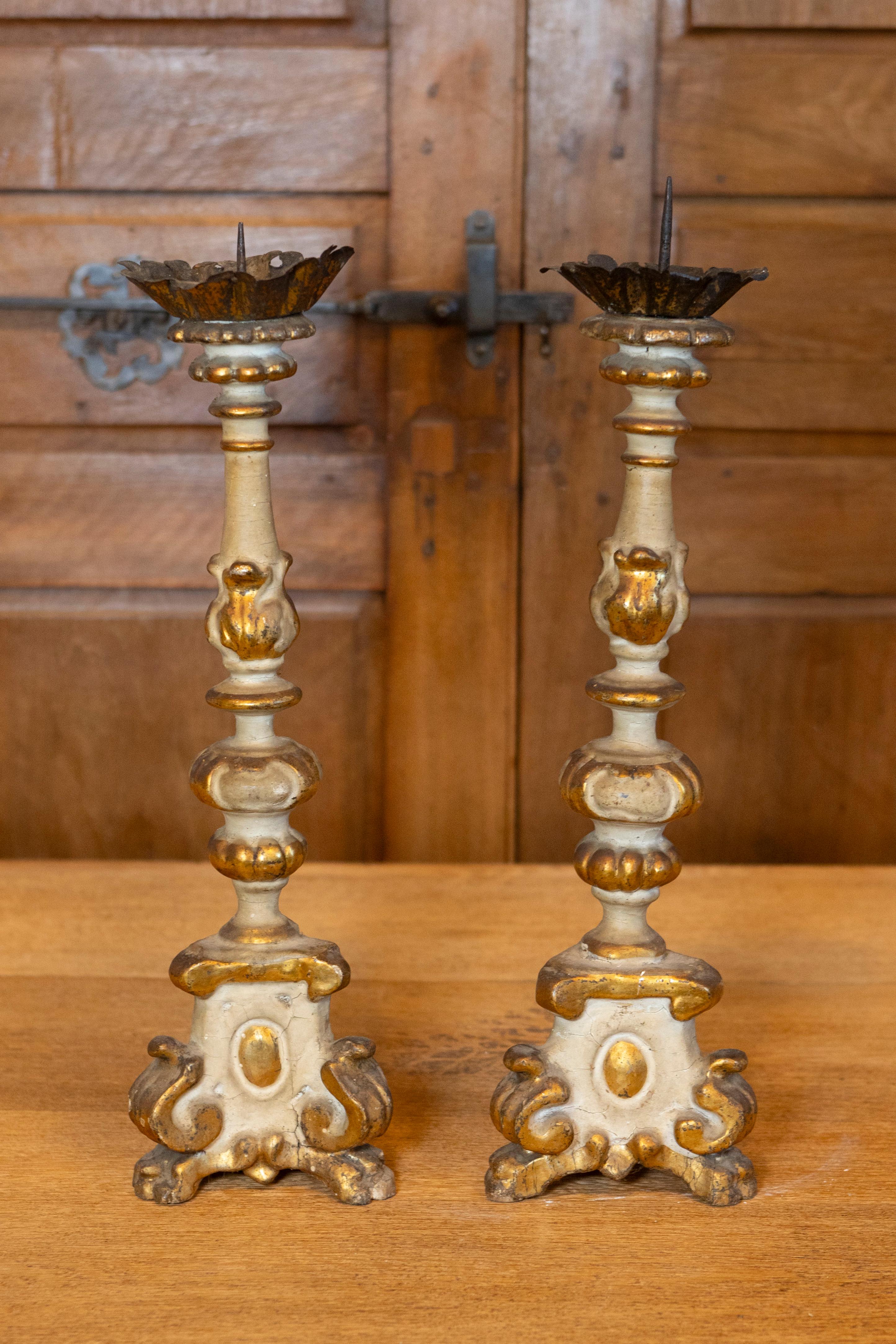 This pair of 20th-century French Rococo style parcel gilt candlesticks is a testament to the grandeur and elegance of classic French design. The light-colored painted ground serves as a perfect canvas for the gilded accents, which highlight the